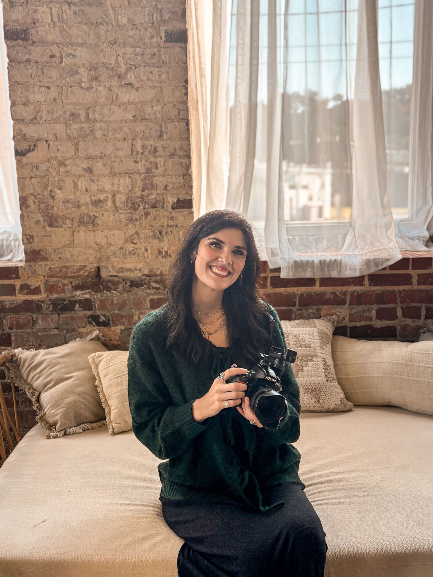 Casual indoor portrait session on couch with exposed brick wall background.