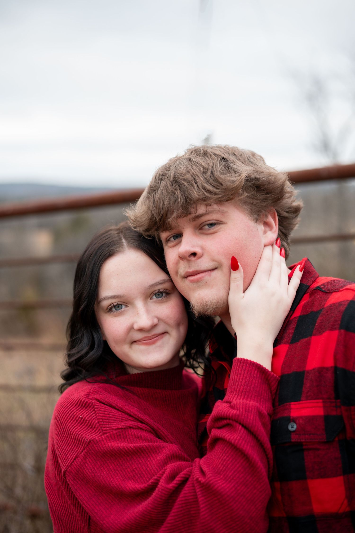 Couple in red winter clothing sharing playful moments outdoors.
