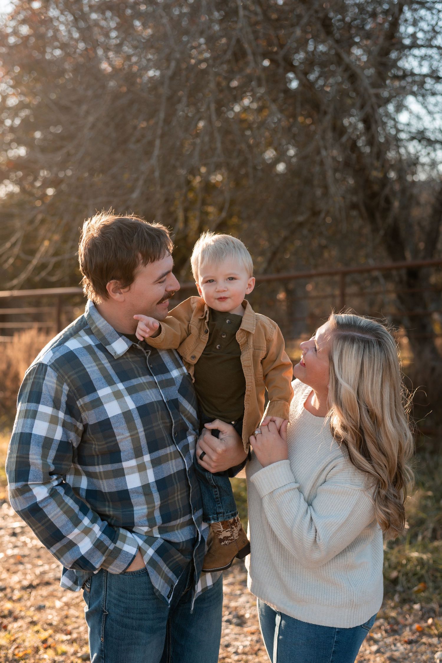 Family shares playful moments together during golden hour autumn photoshoot in fallen leaves.