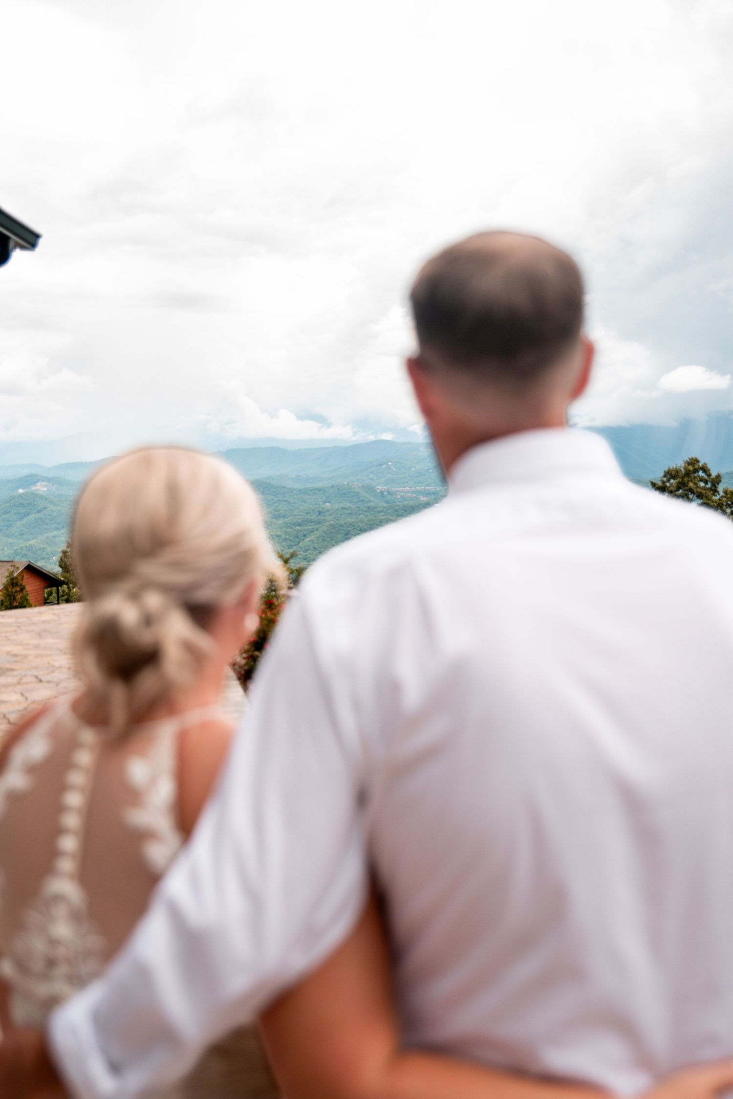 Bride and groom stand together admiring scenic mountain views on their wedding day.