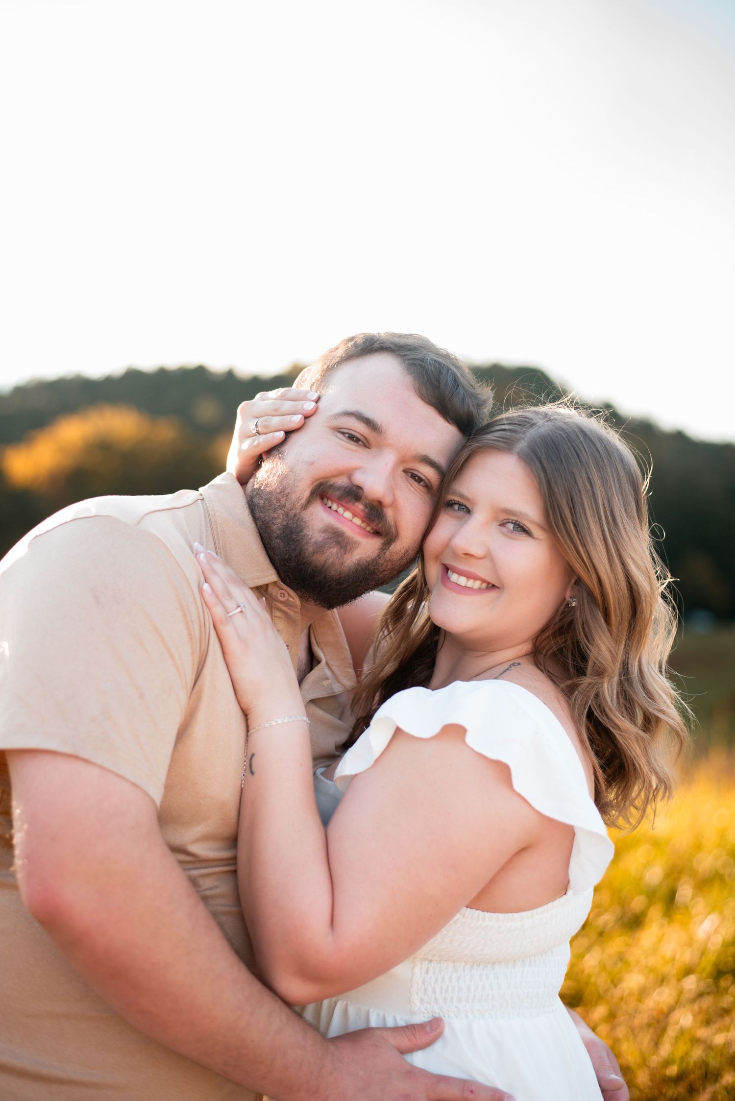 Loving couple embracing and laughing together during sunset engagement photos.