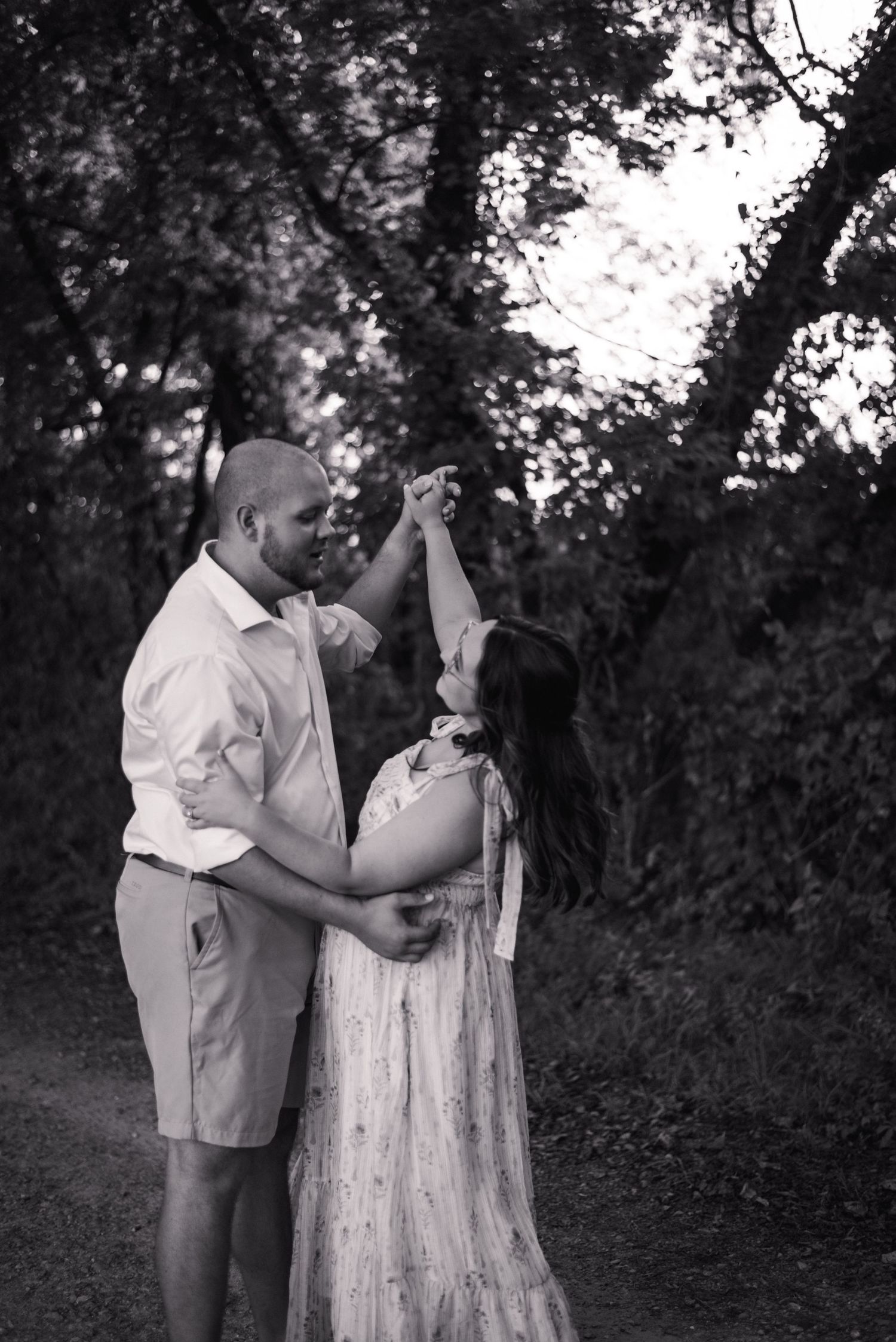 Black and white photo of a couple dancing and embracing outdoors in a romantic moment.