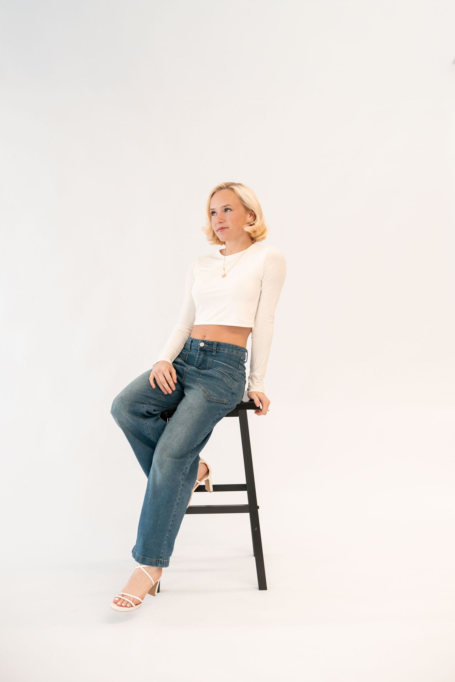 Studio portraits showing various seated poses on black chair against white background.
