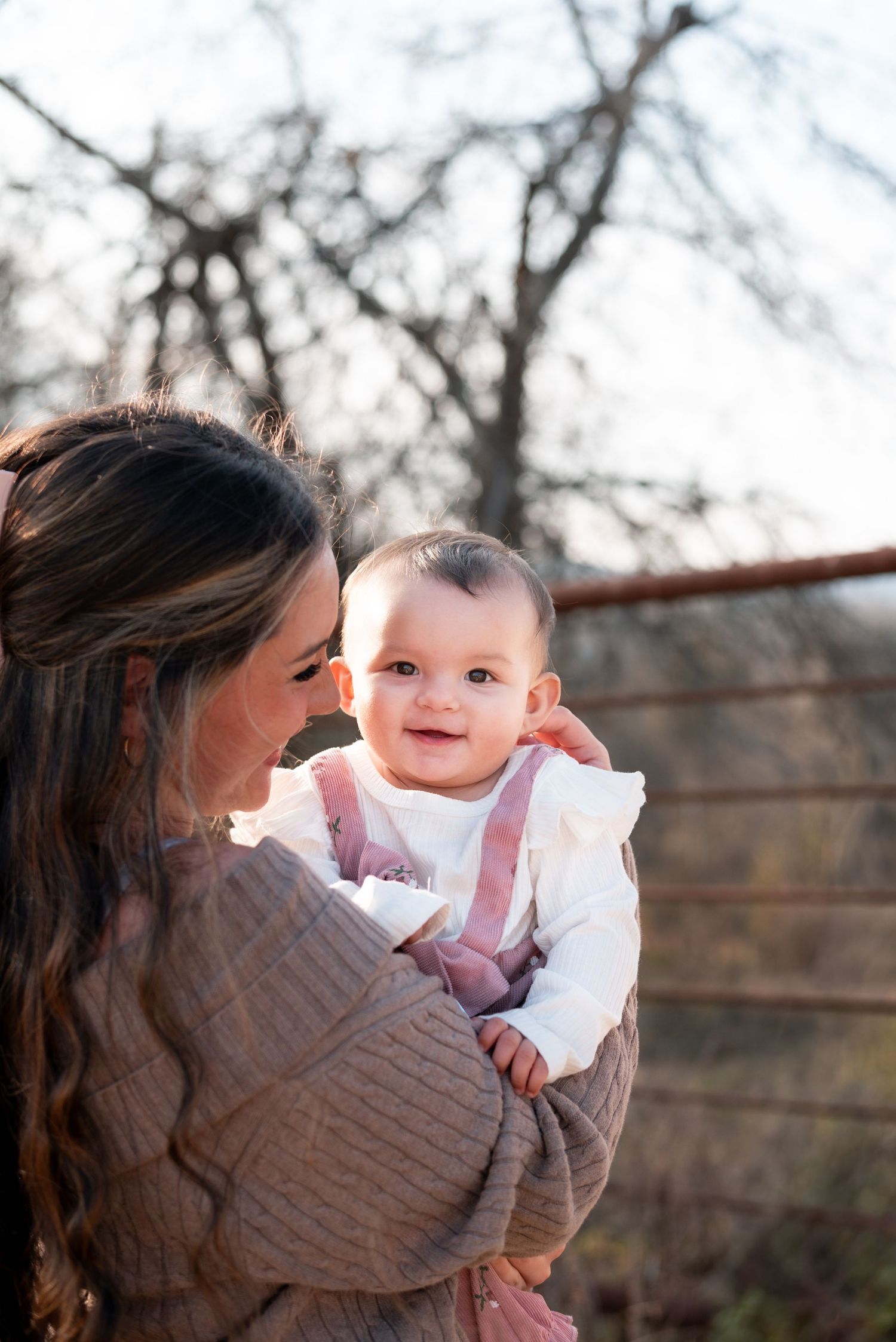 Baby in pink outfit sharing a sweet moment with parent outdoors.