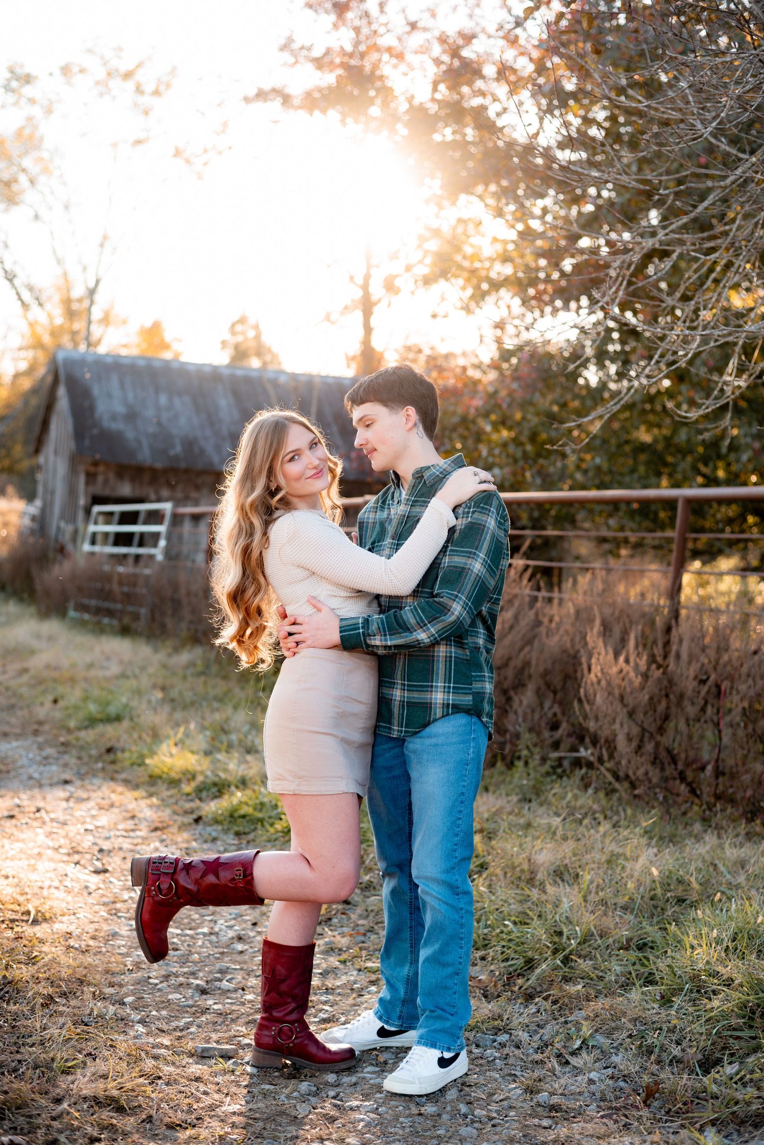 A couple dances and laughs together on a dirt path at sunset.