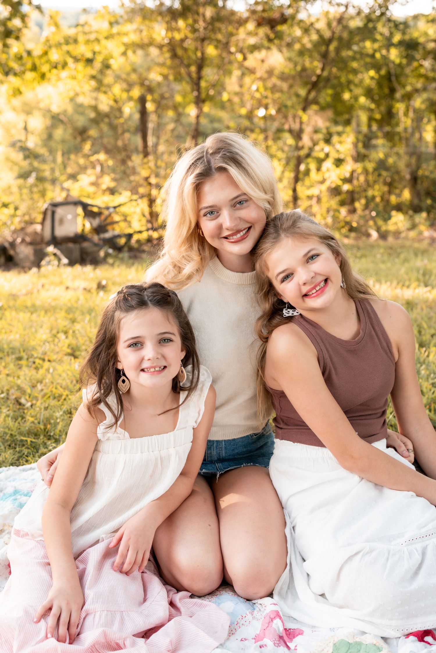 Group sits together on blanket for casual outdoor portraits in golden sunlight.