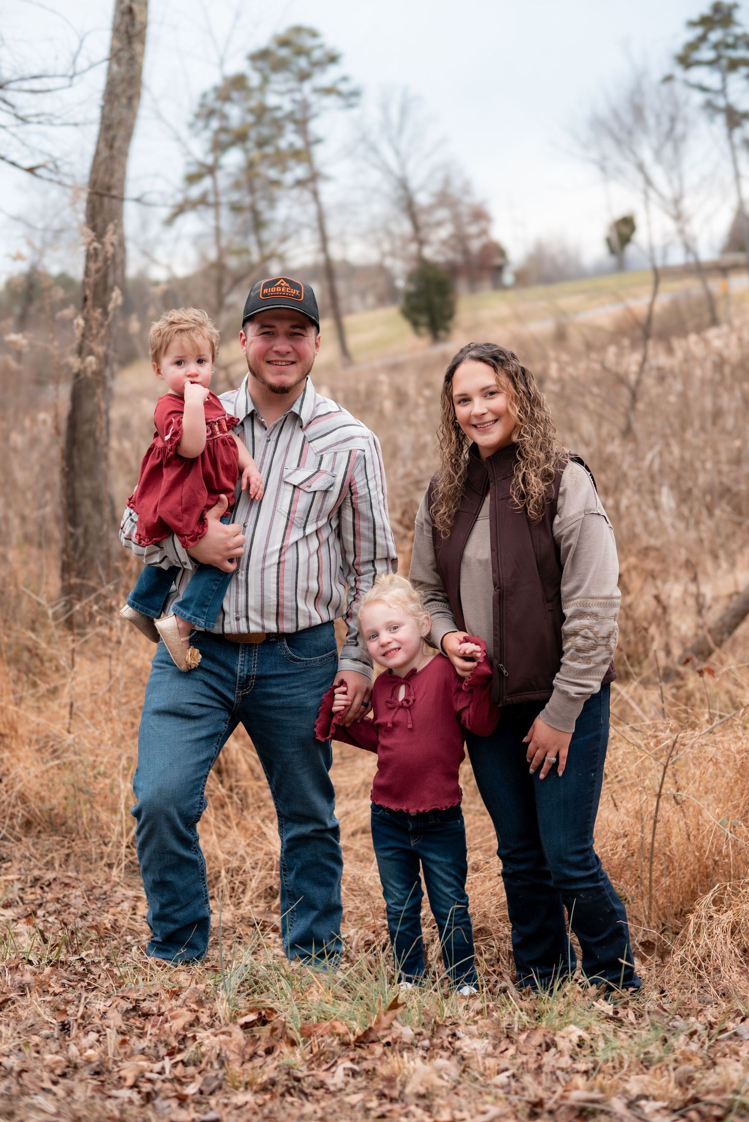 Family portrait series taken in a rustic outdoor setting with fall foliage.