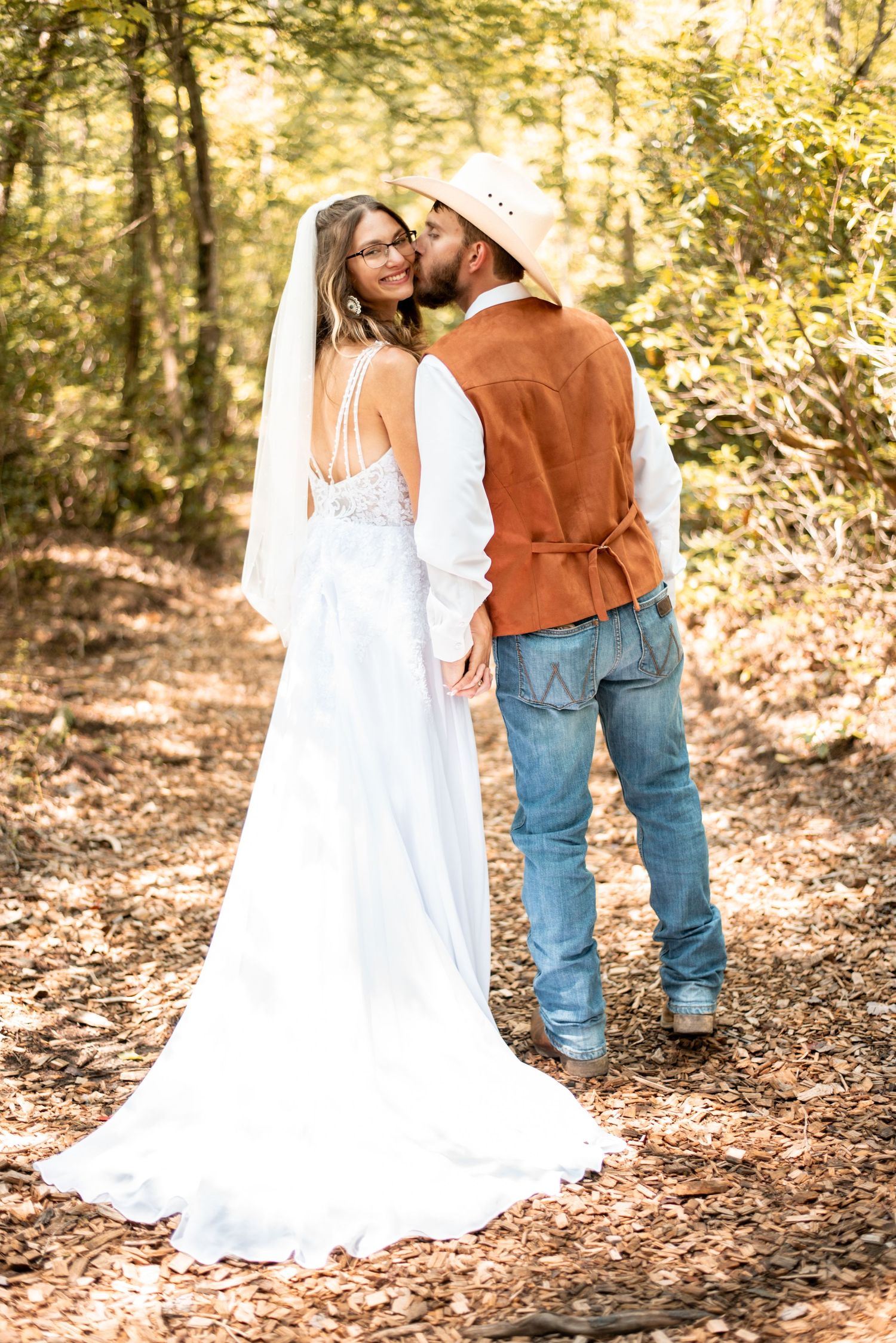 Romantic couple in wedding attire embracing among autumn leaves.