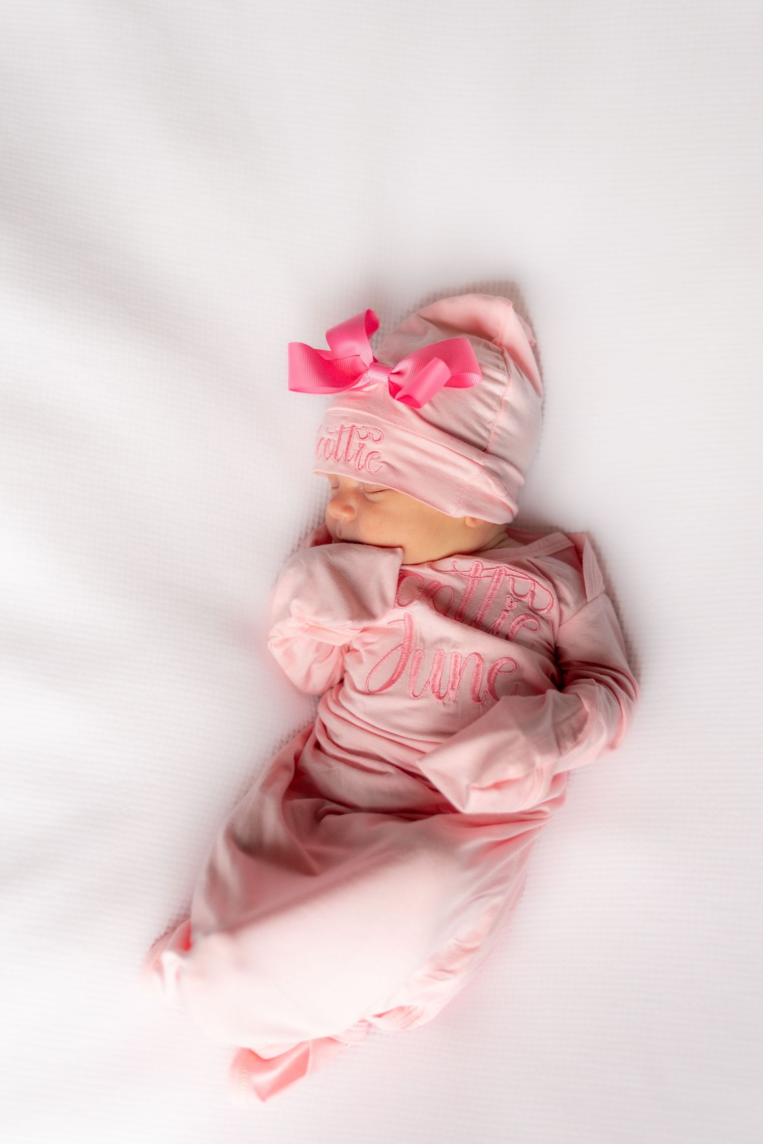 Pink baby clothes and accessories arranged artistically on white background.