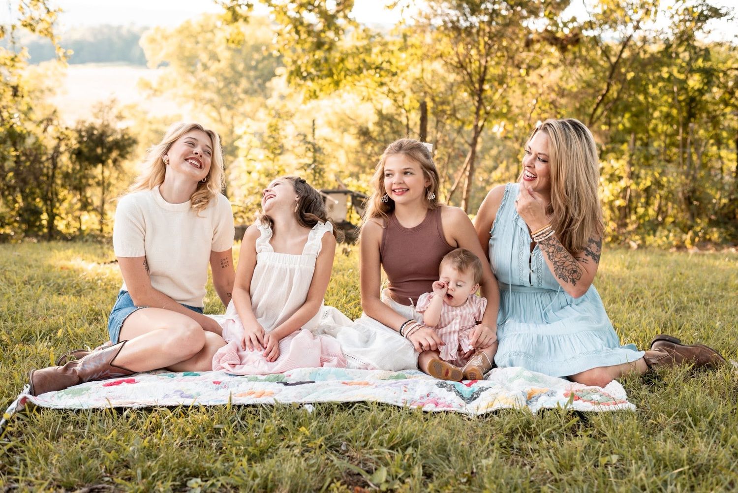 Family picnic gathering on blanket during golden hour in grassy field.