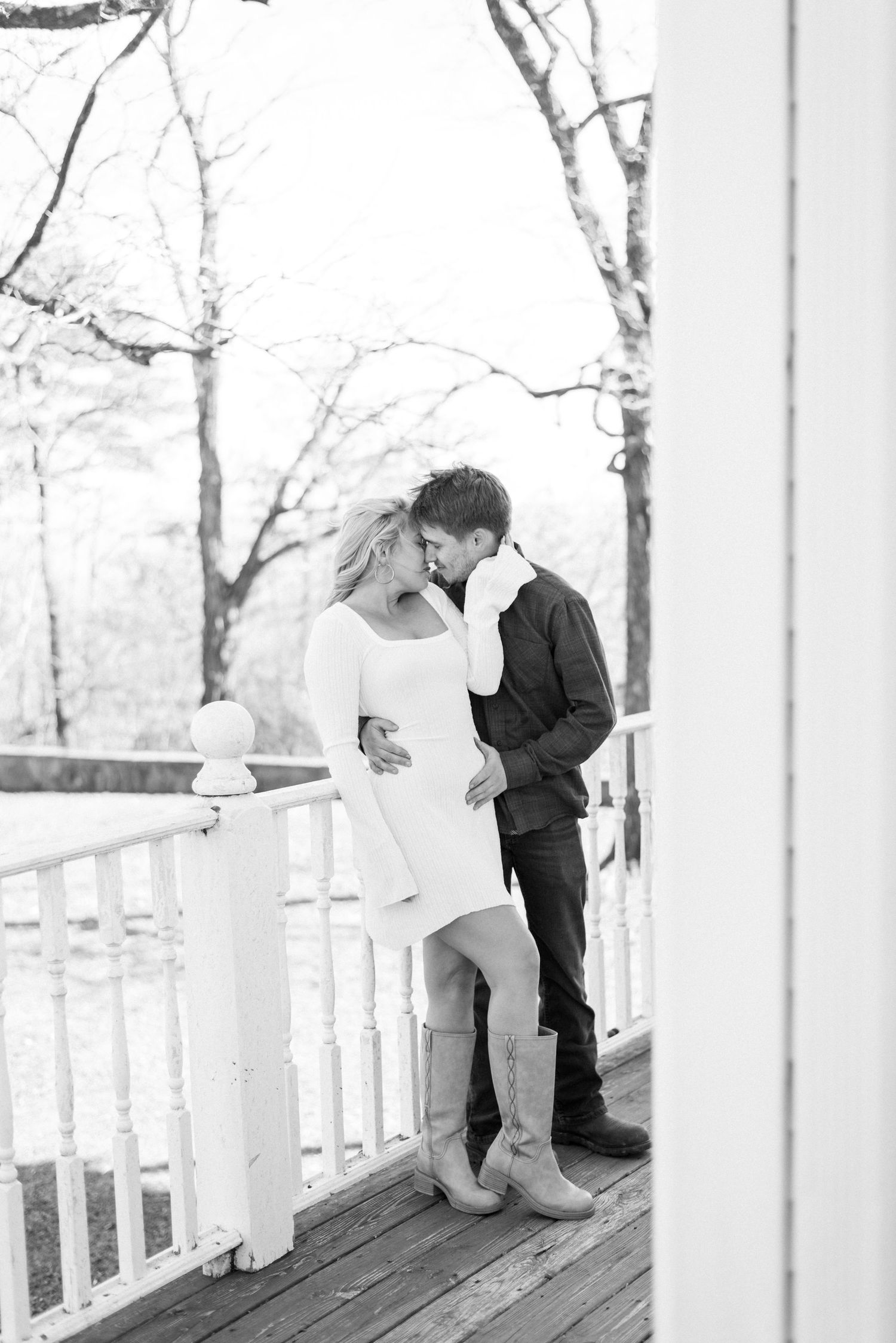 Two people share an intimate moment on a white porch railing in winter.
