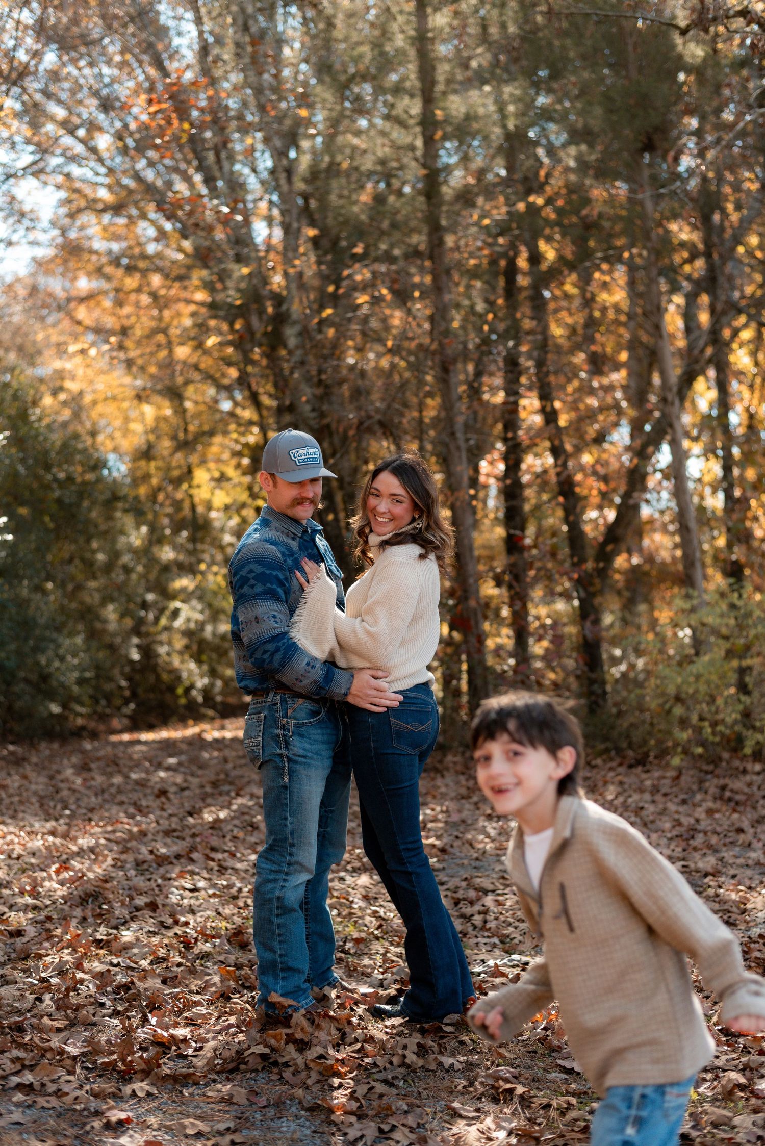 Playful family photos in autumn woods with fallen leaves.
