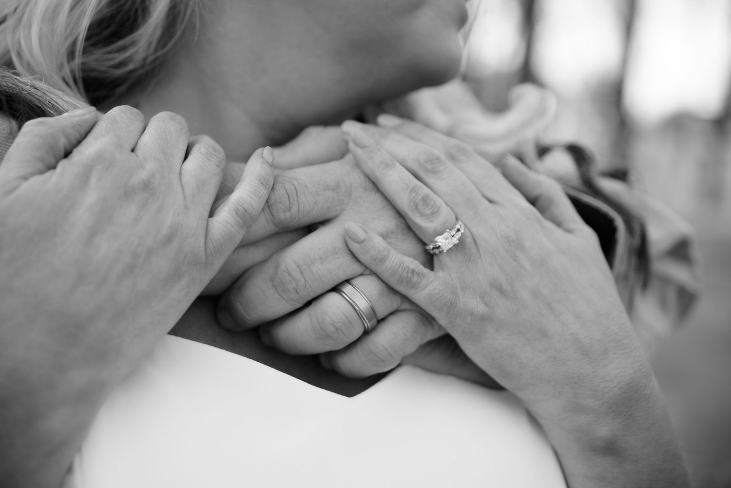 Black and white photo of a couple holding hands showing wedding rings.