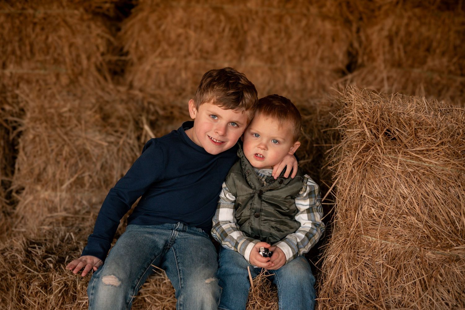 Cozy family moments captured in warm tones against rustic autumn field backdrop.