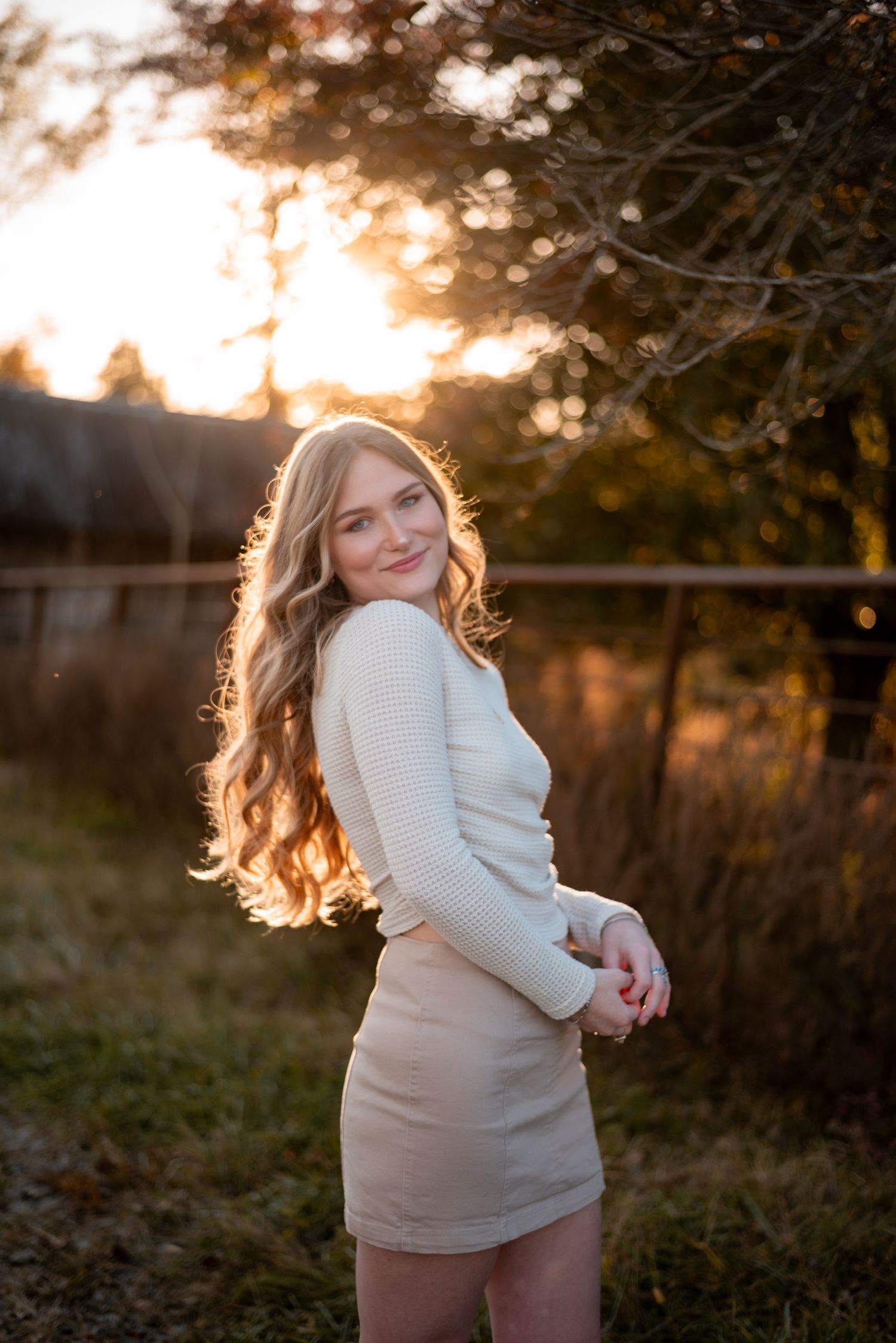 Side profile portrait in a field during sunset with warm backlighting.