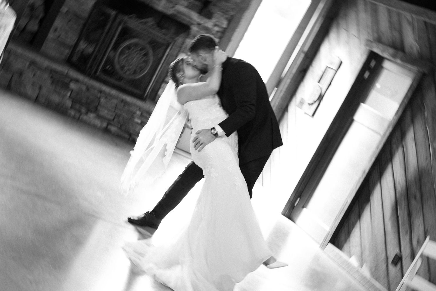 A dramatic black and white photo of newlyweds dancing in an elegant venue.