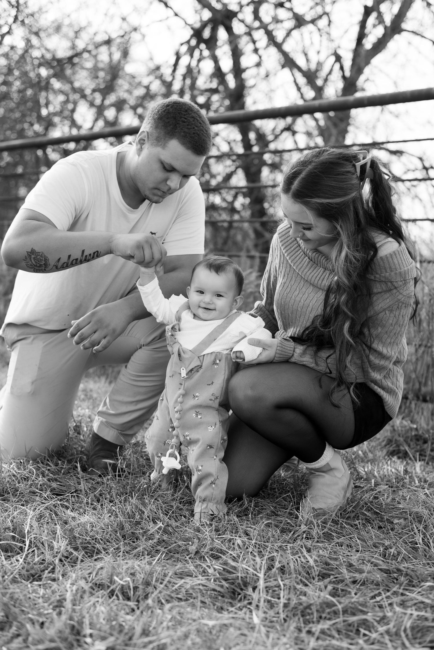 Black and white series showing sweet interactions while sitting together in grassy outdoor setting.
