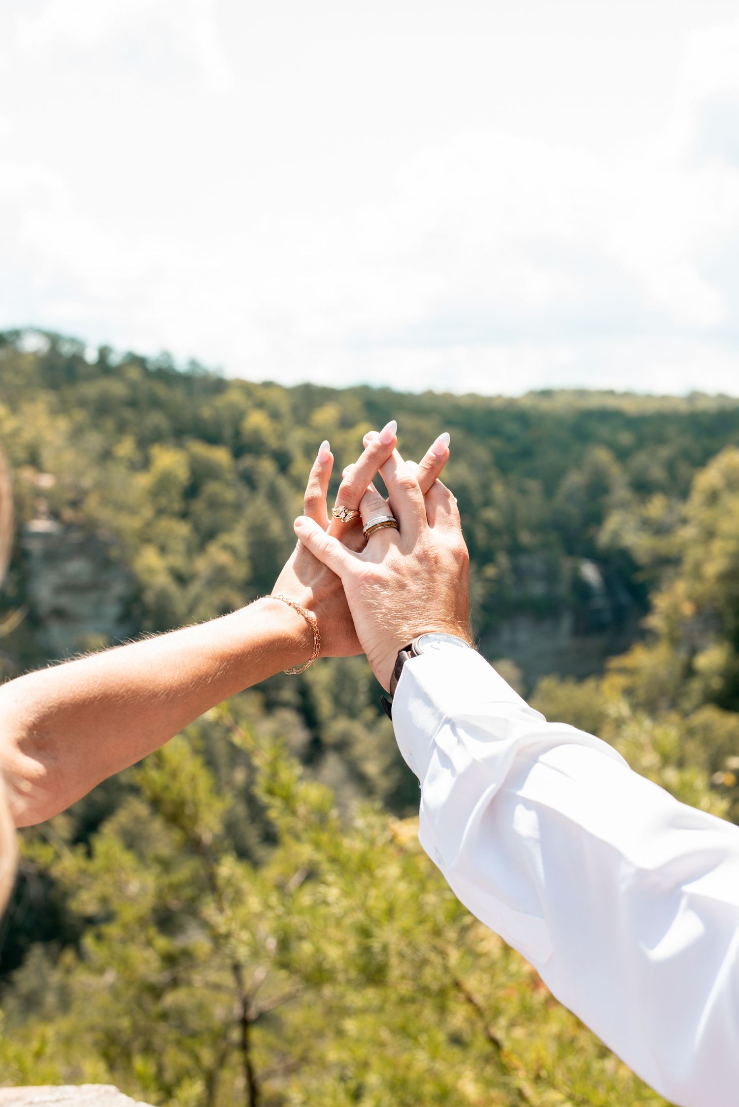 Hands raised against a scenic mountain landscape background in white sleeves.