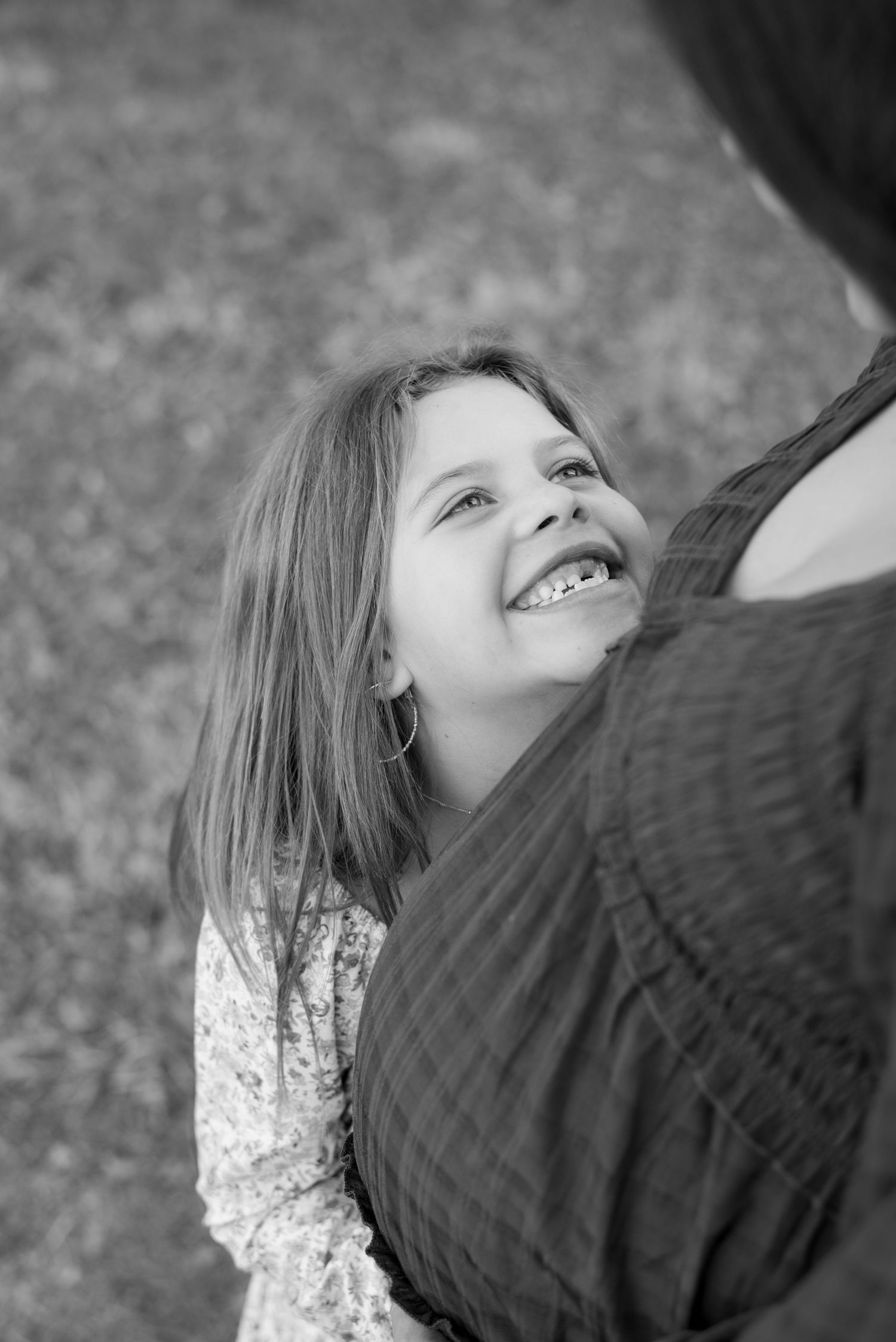 Child looking up with joy while playing outdoors on a cloudy day.