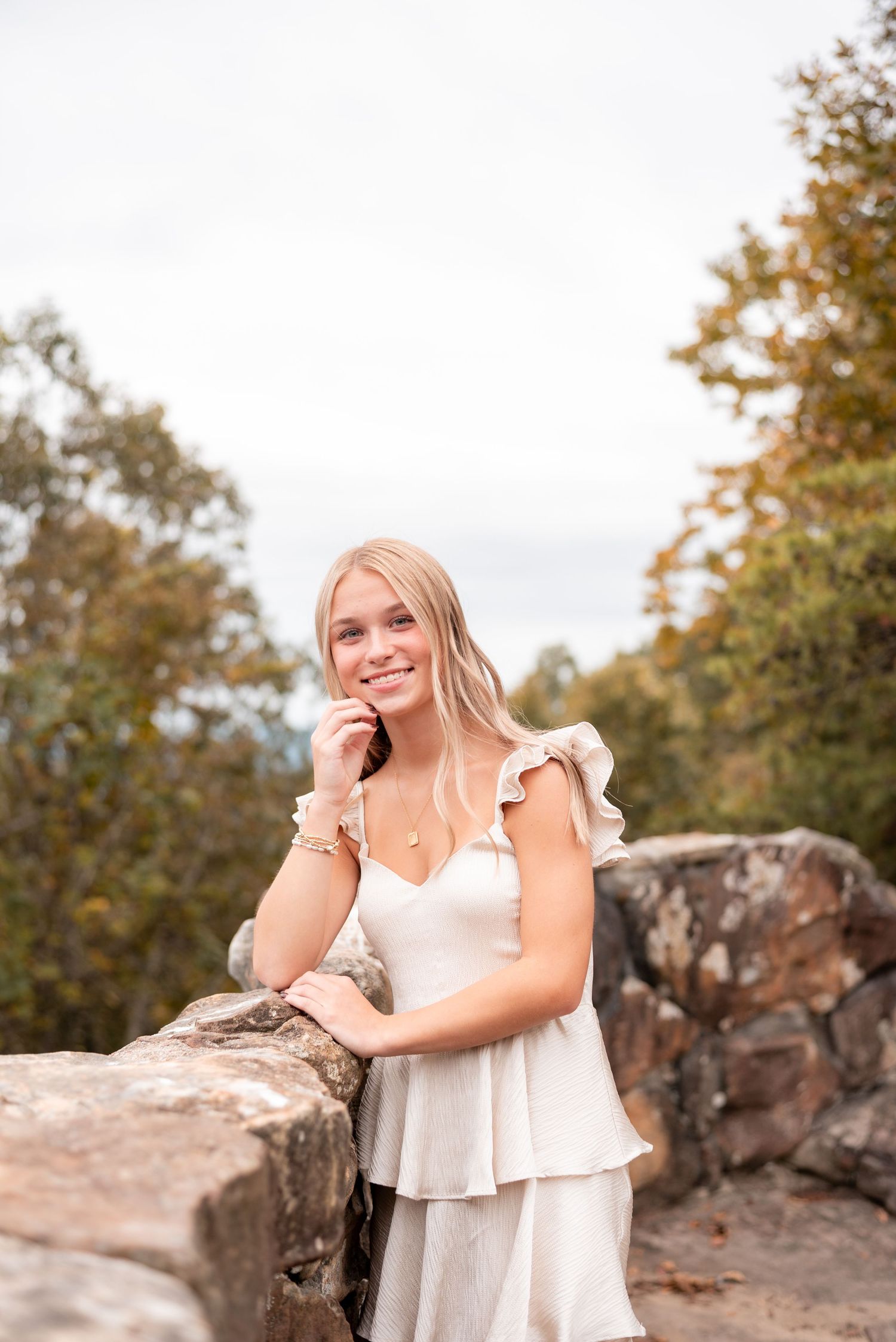 Portrait session by weathered rock wall wearing a light colored ruffle dress.