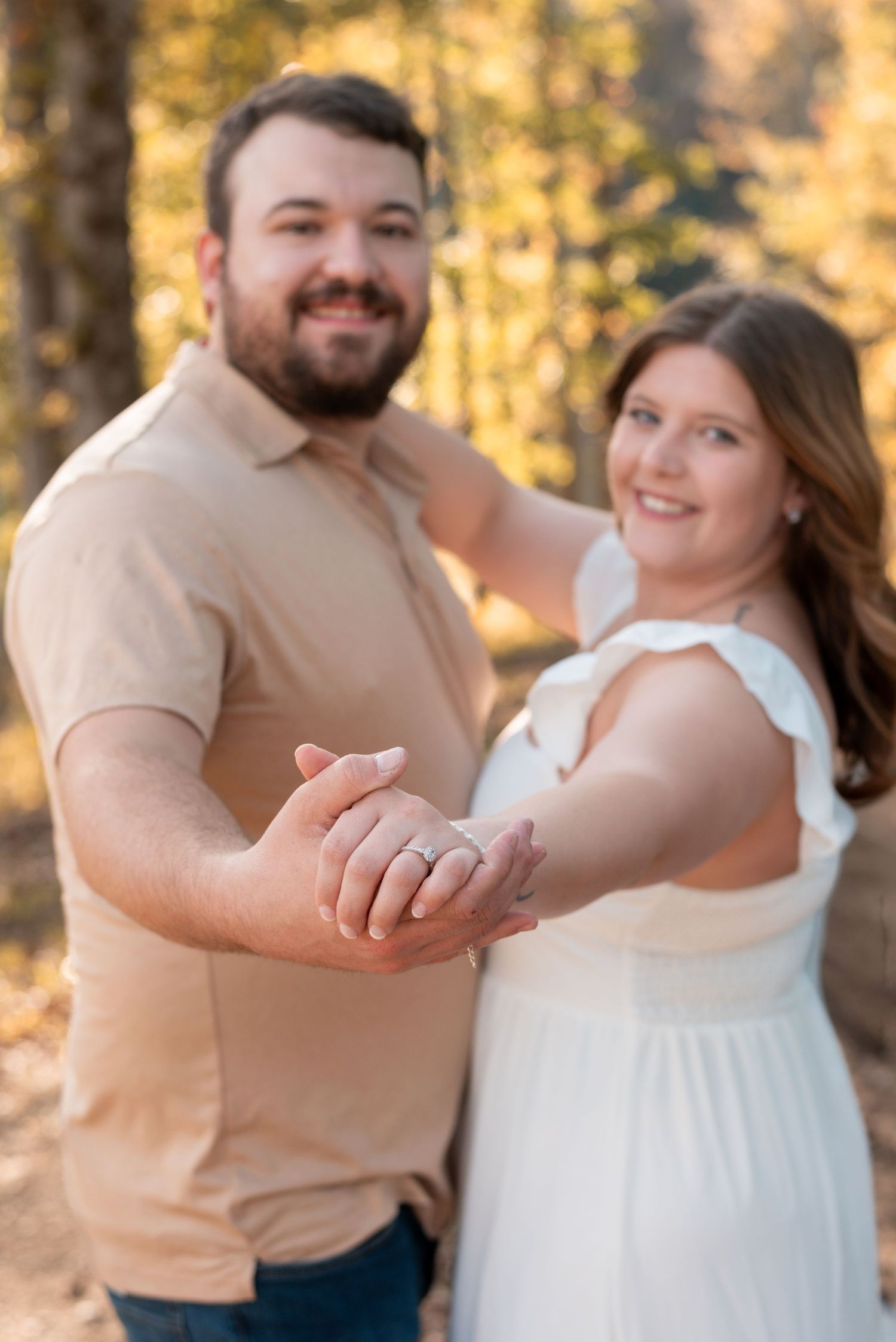 A couple shares a joyful moment together during an outdoor photoshoot in autumn light.