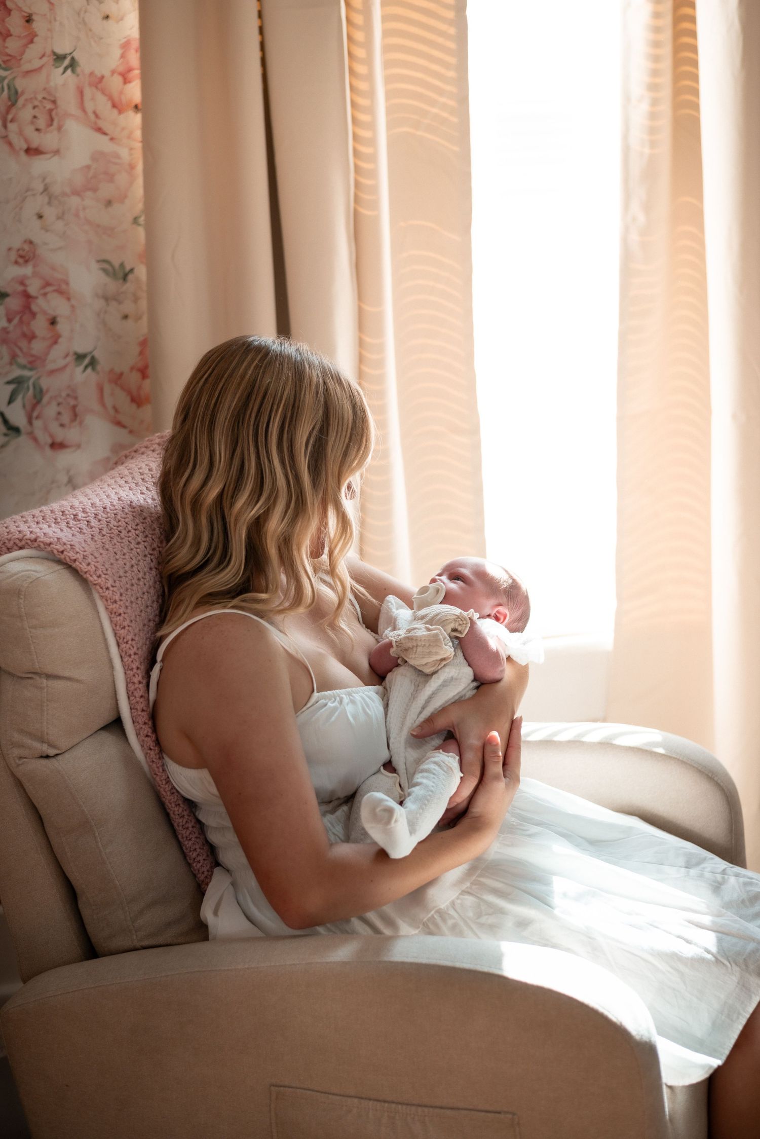 Tender moment between parent and newborn in soft window light.
