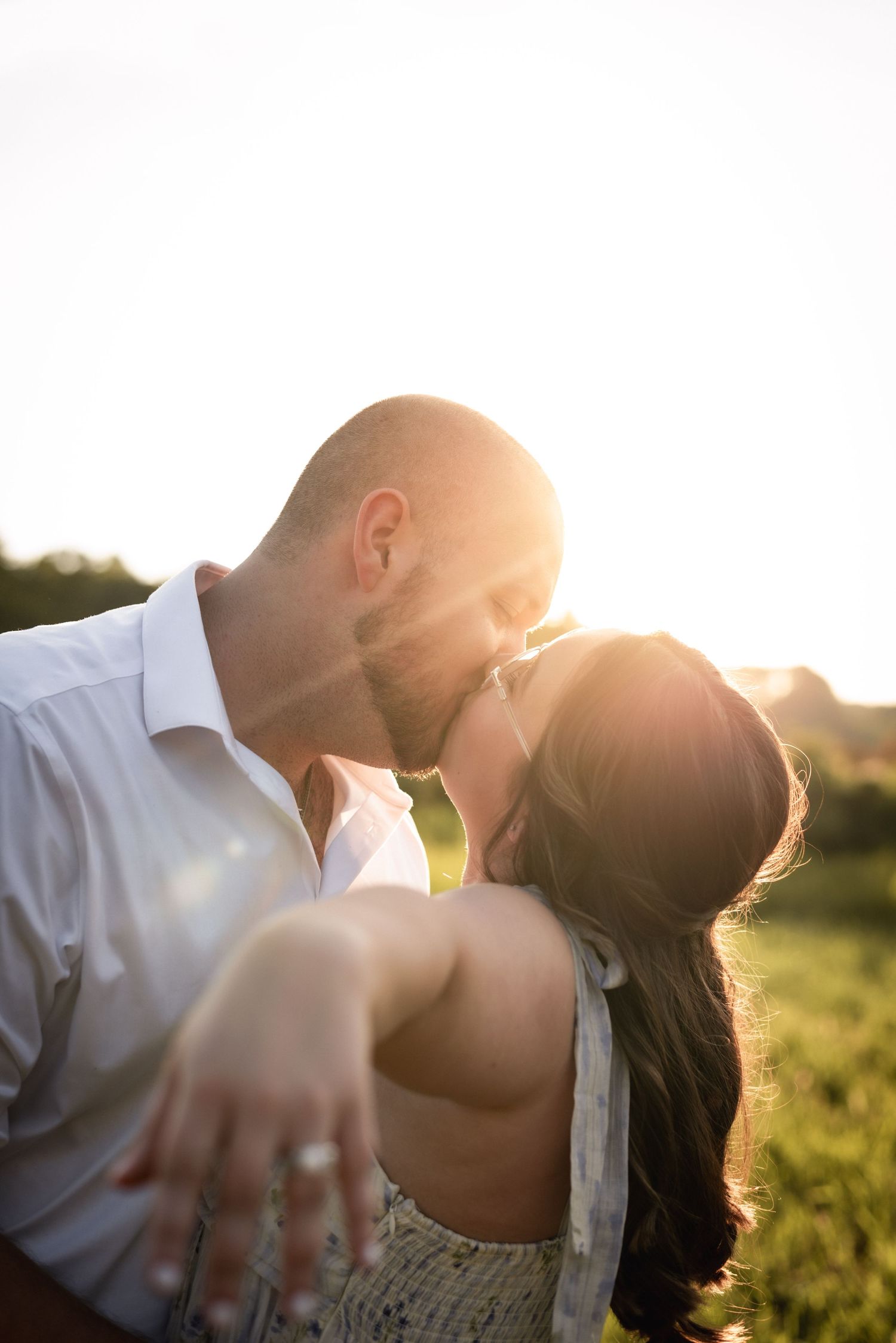 Couple sharing tender moments at sunset in a natural outdoor setting.