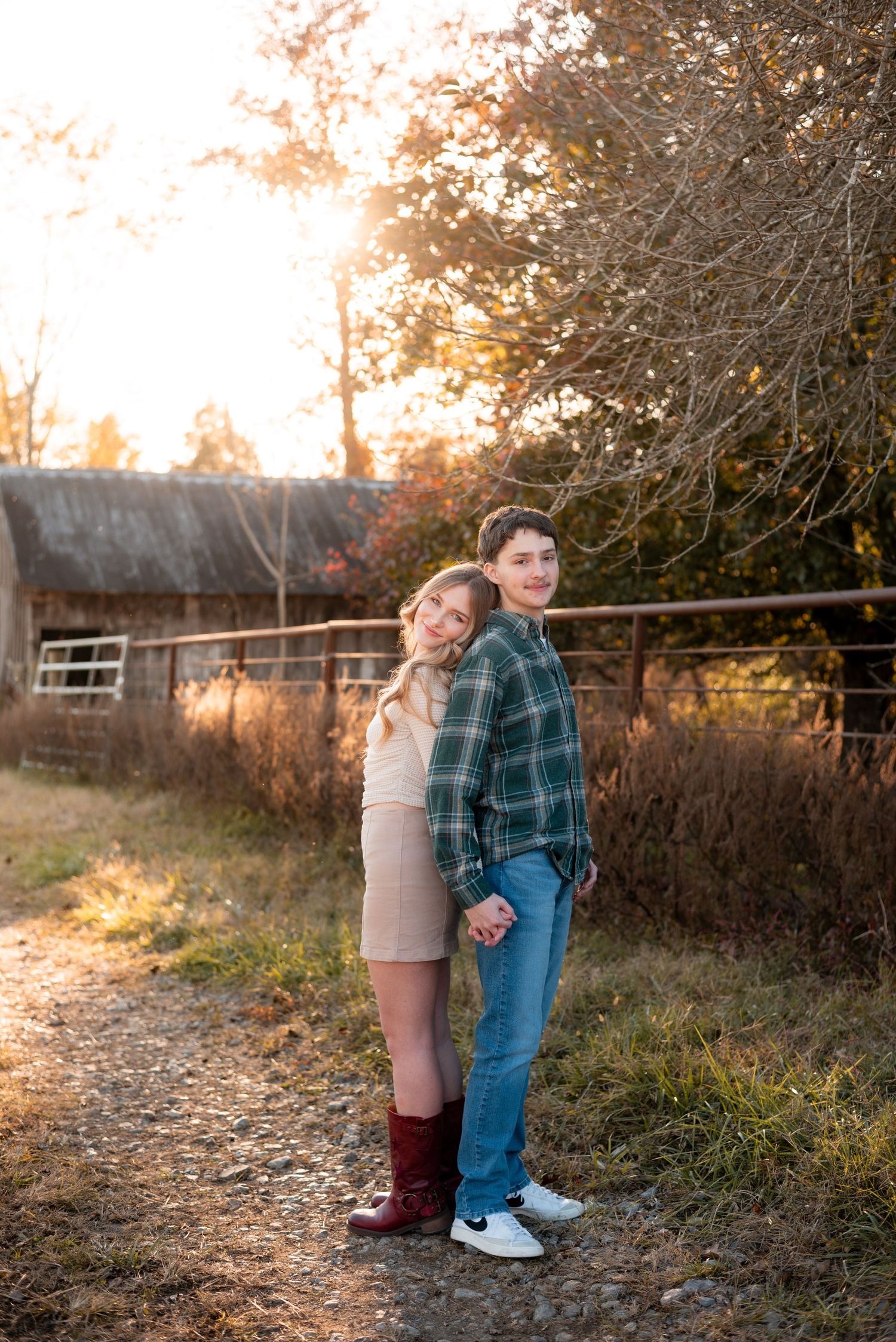 A couple playfully interacts in a rustic outdoor setting during golden hour.