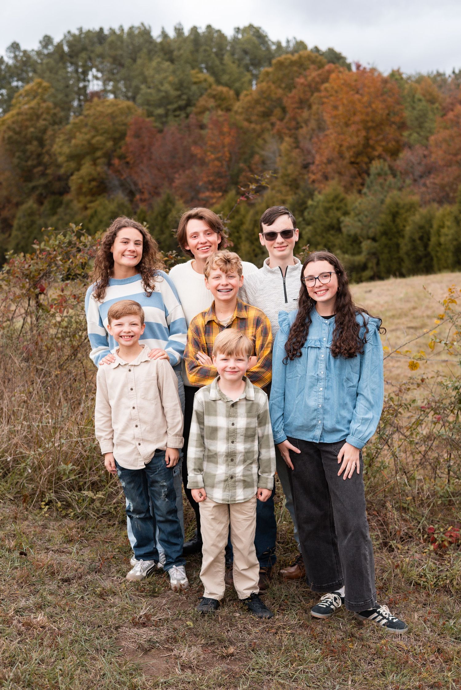 Group photo taken in a fall field with autumn foliage in the background.