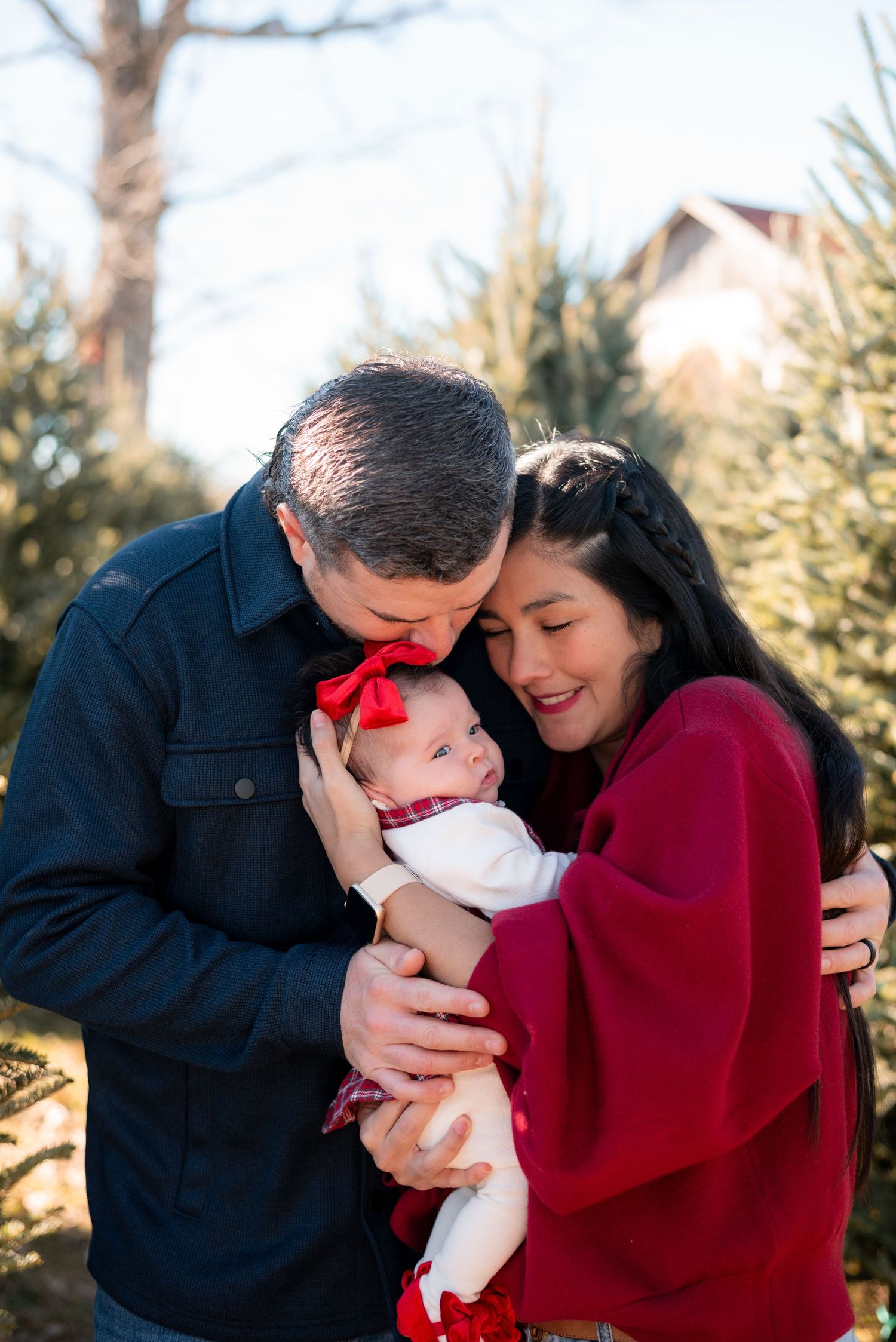 Family sharing intimate moment together near pine trees in winter clothing.