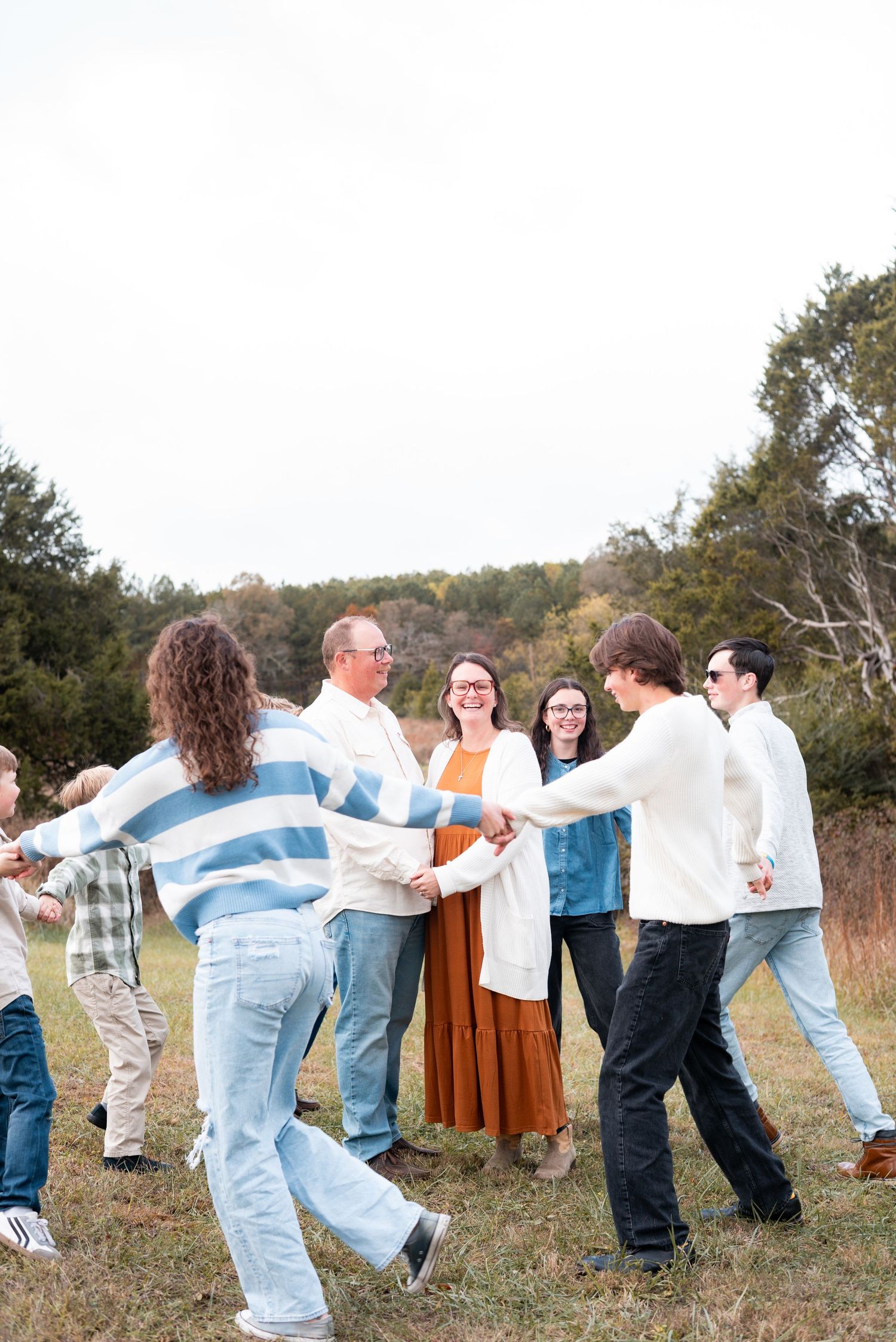 People holding hands in a long line across a scenic autumn field.