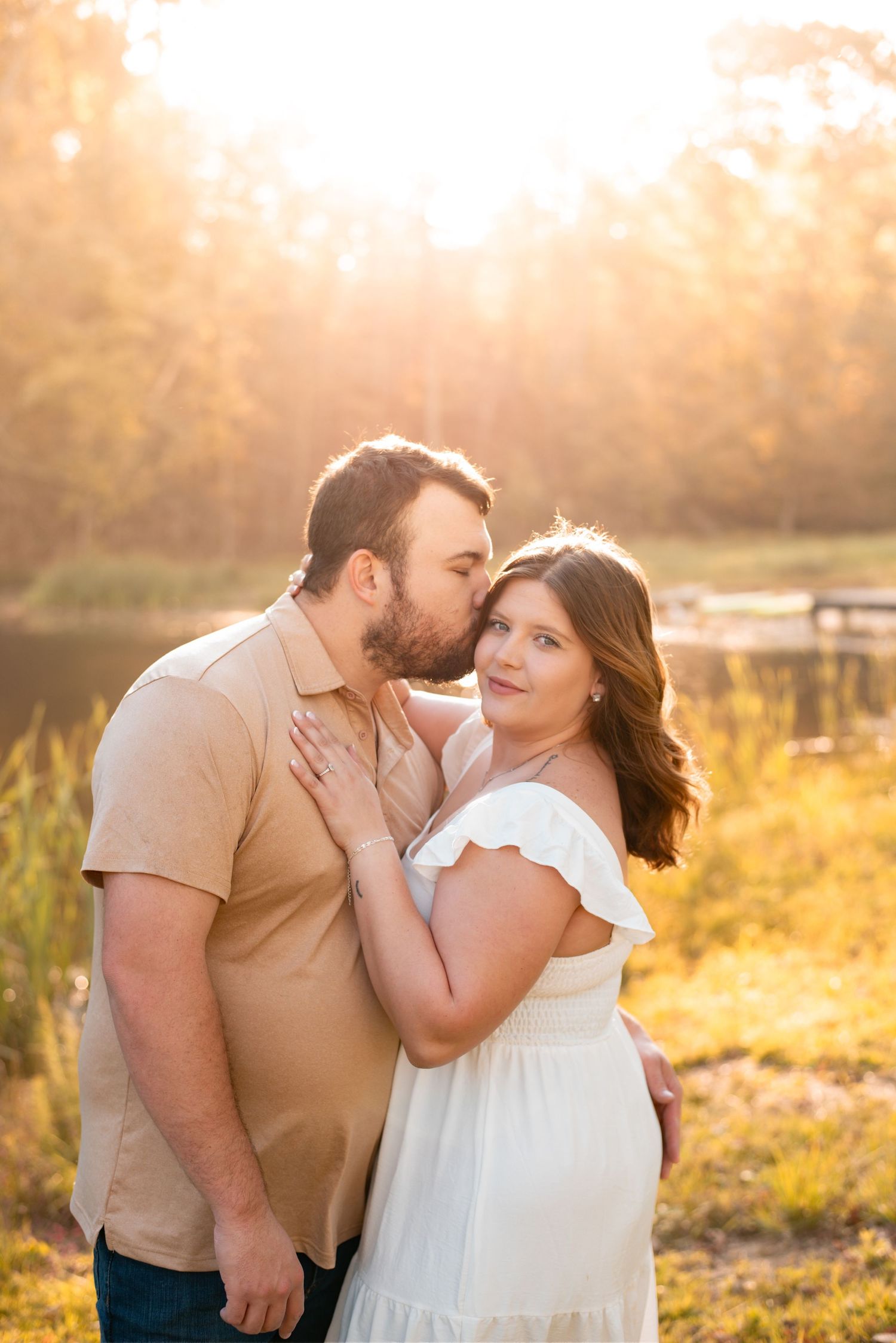 Couple sharing affectionate moments in a sun-drenched field at golden hour.