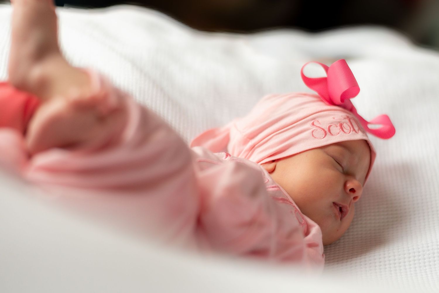 Delicate newborn baby toes wrapped in pink blanket with soft focus background.