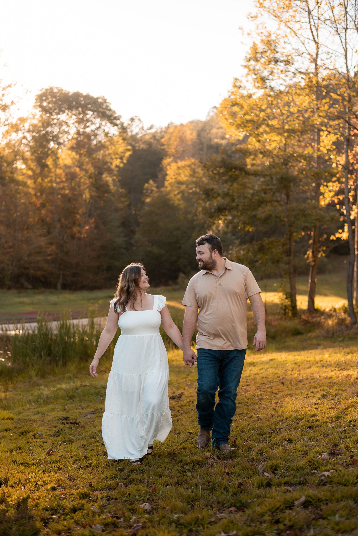 Couple walking together through a sunlit meadow during golden hour.