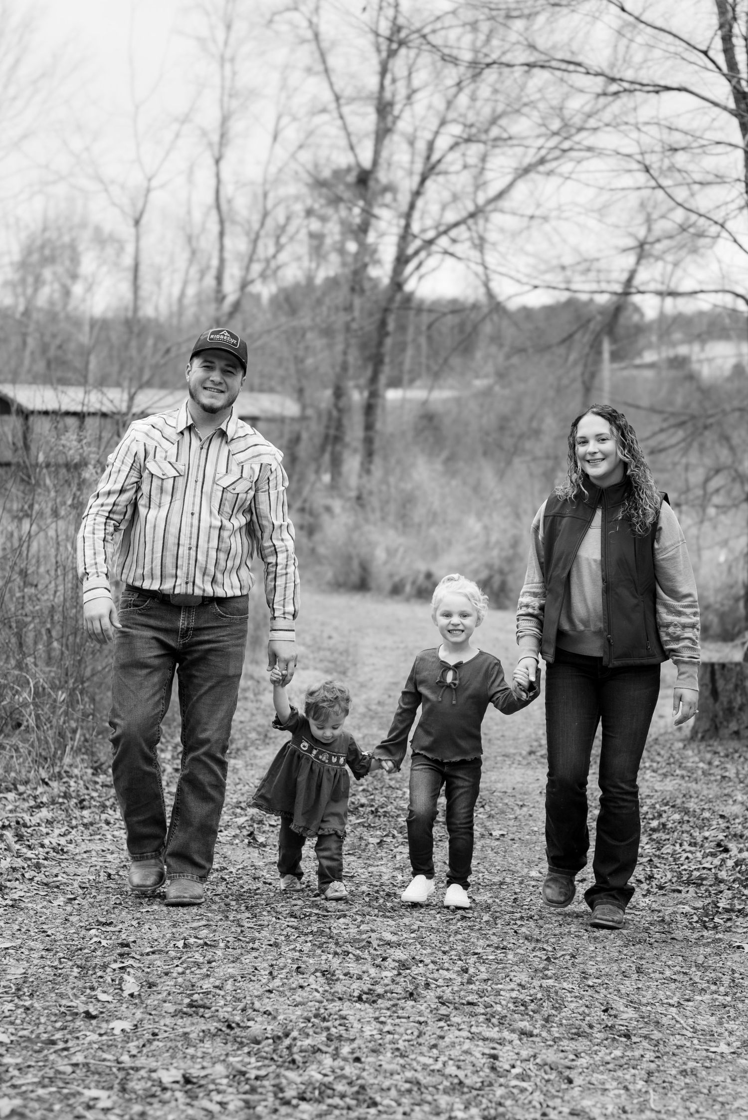Black and white series of a family walking together through fallen leaves on a path.