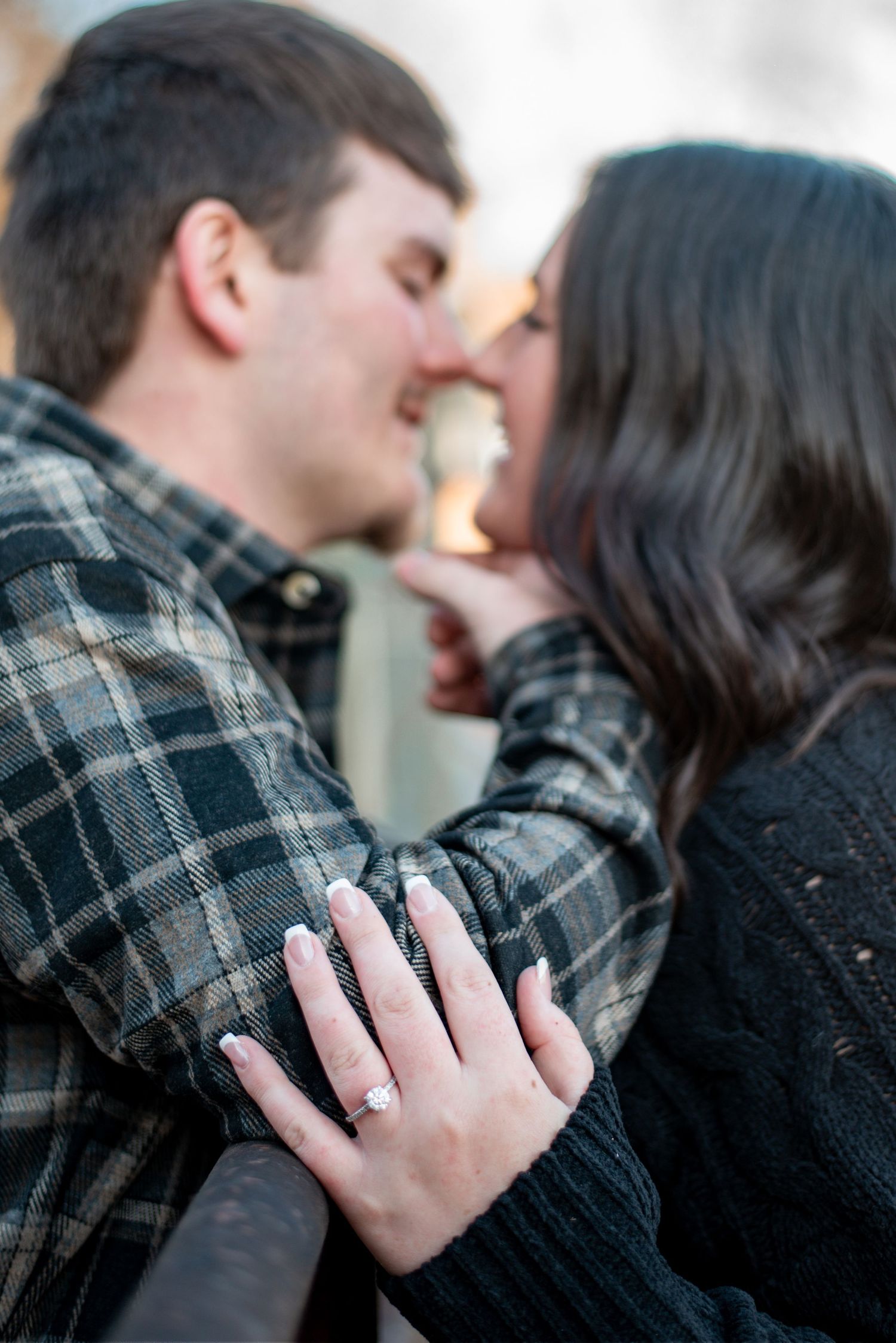 Intimate engagement photo showing ring while couple shares a romantic moment.