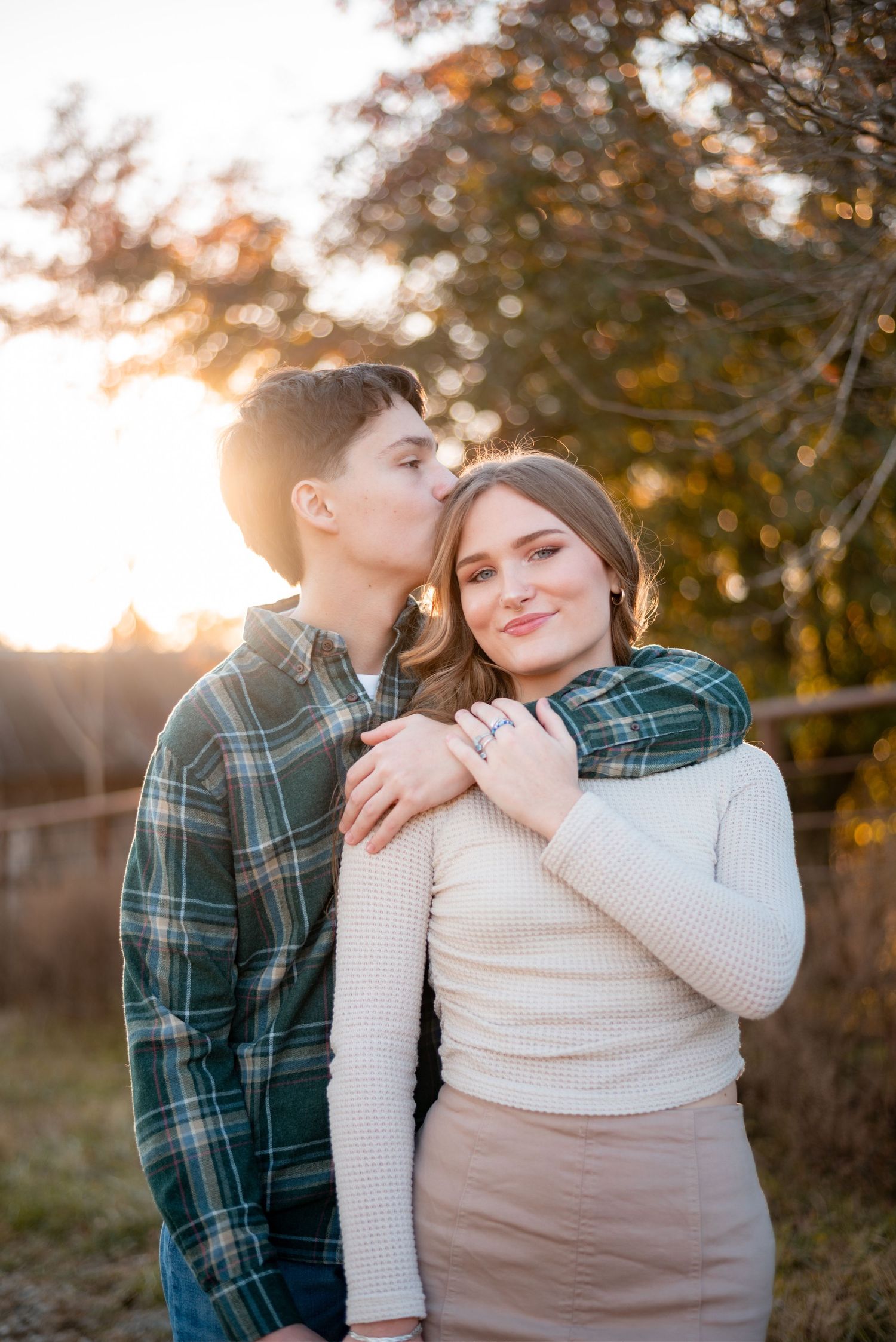 A couple embraces in warm evening light against an autumn backdrop.