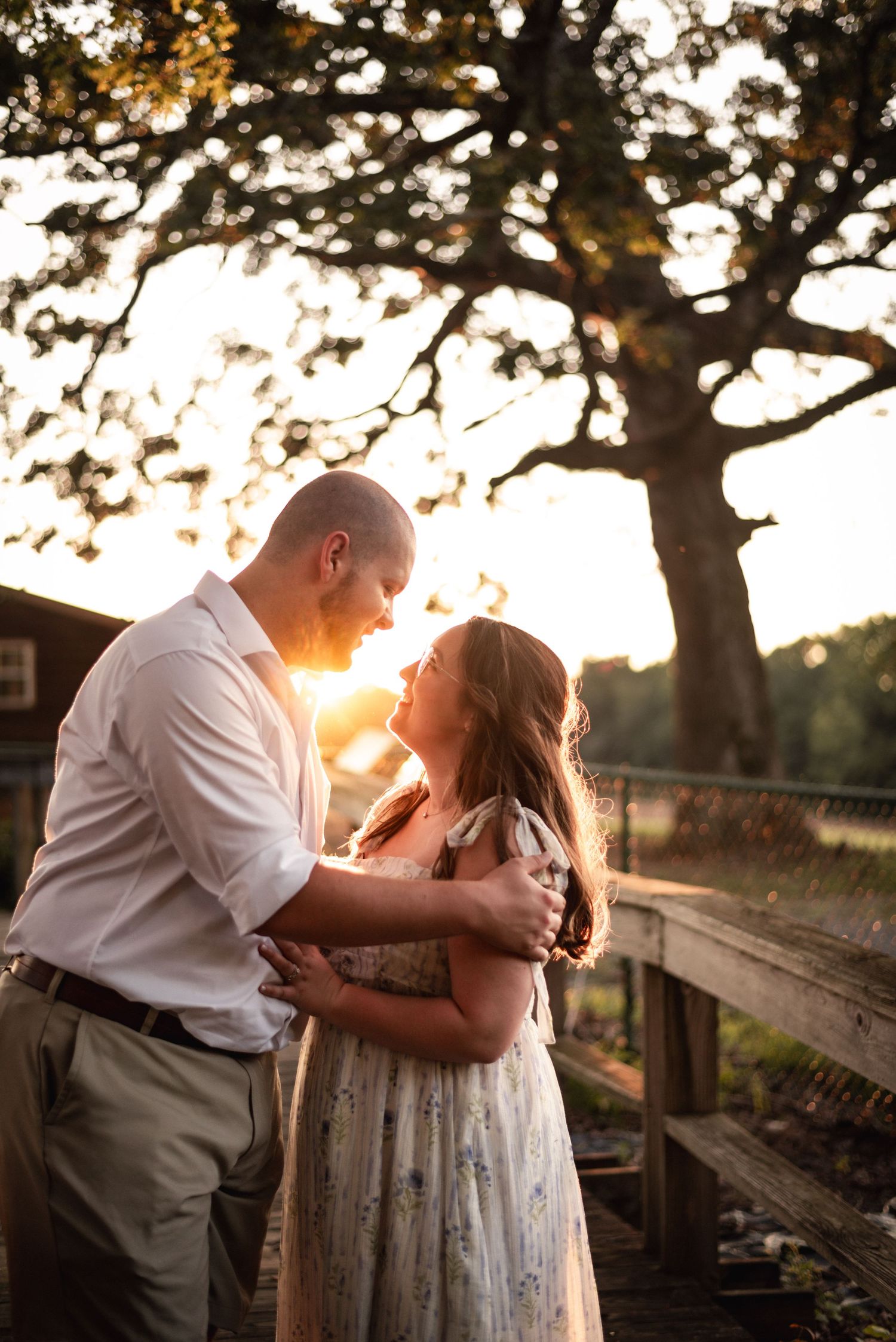 Romantic sunset engagement photos by wooden fence.