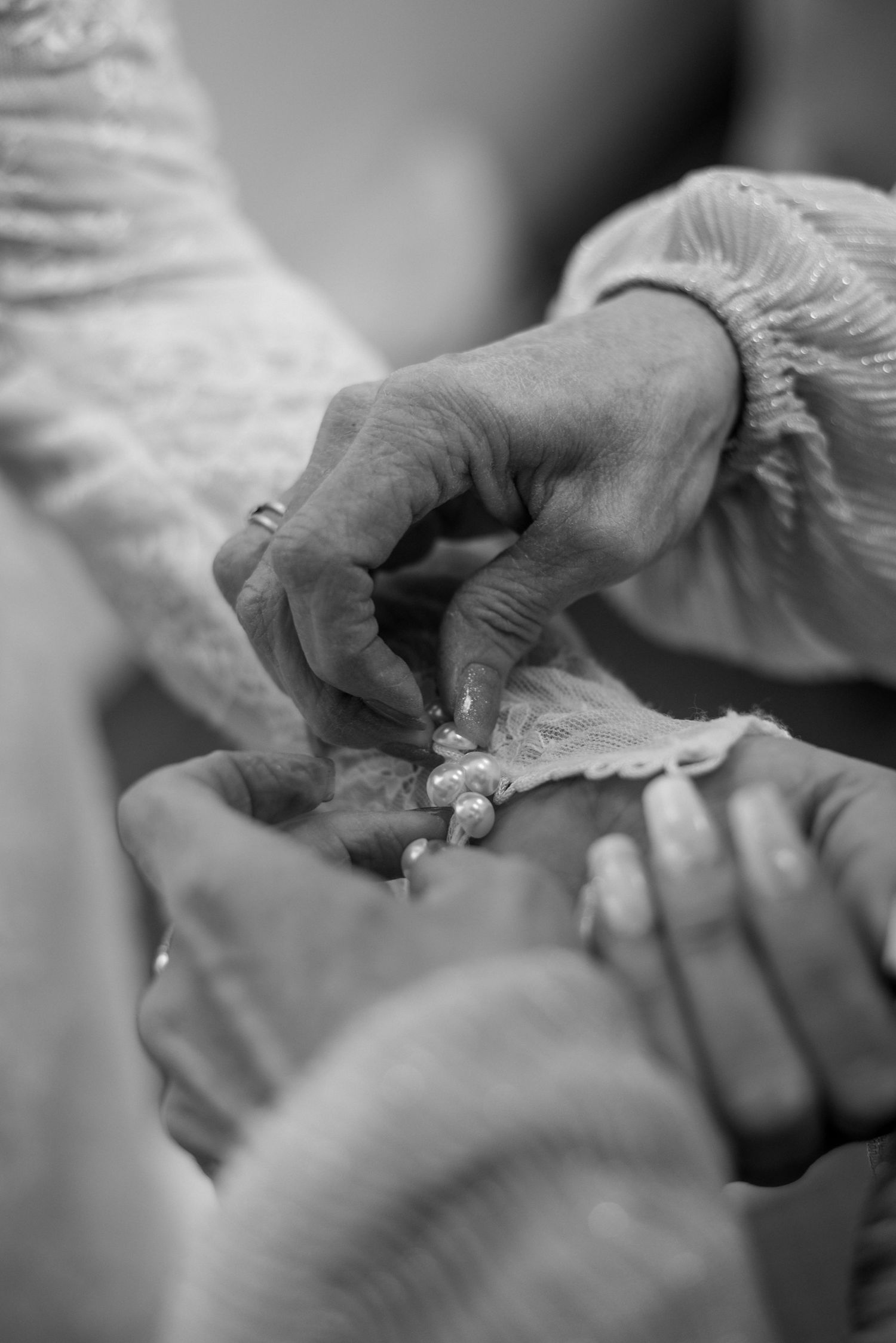 Black and white close-up of hands exchanging wedding rings during ceremony.