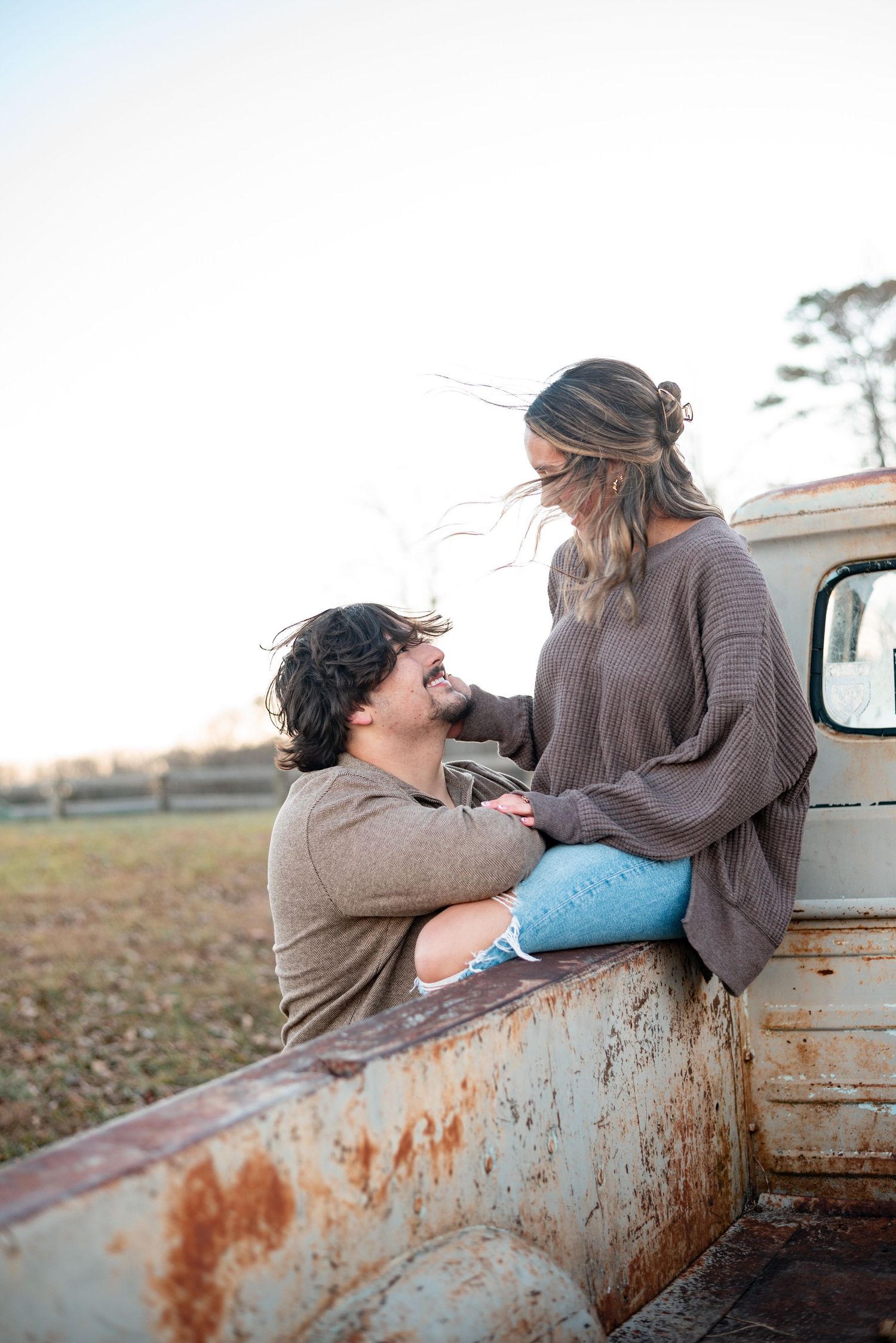 Romantic moment captured against the rusty bed of an old pickup truck during sunset.
