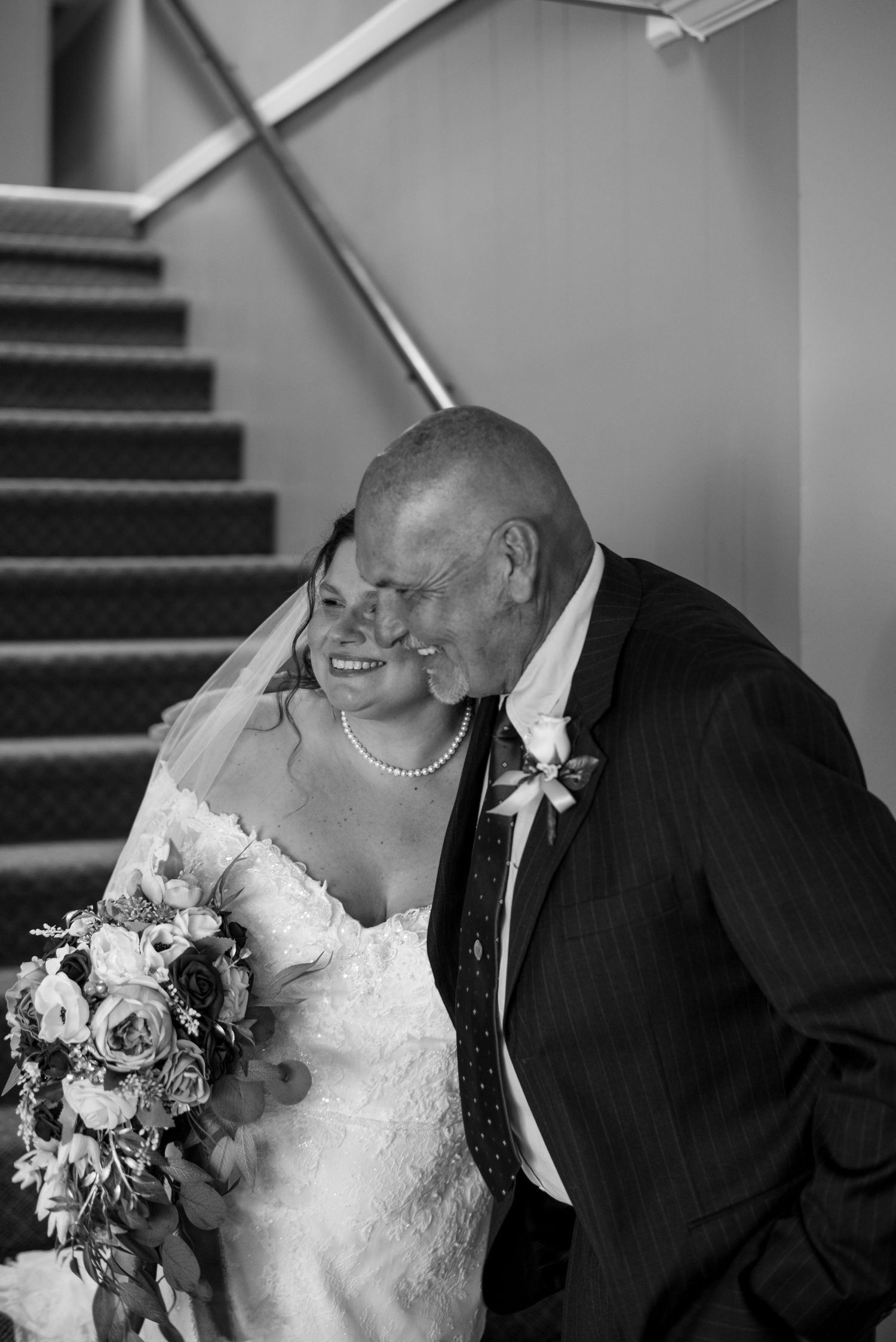 Black and white portrait of tender wedding moment on staircase.