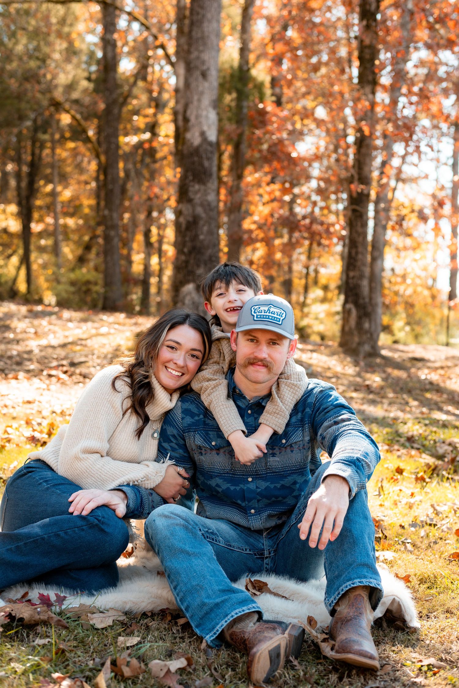 Casual family photos on ground with fallen autumn leaves.
