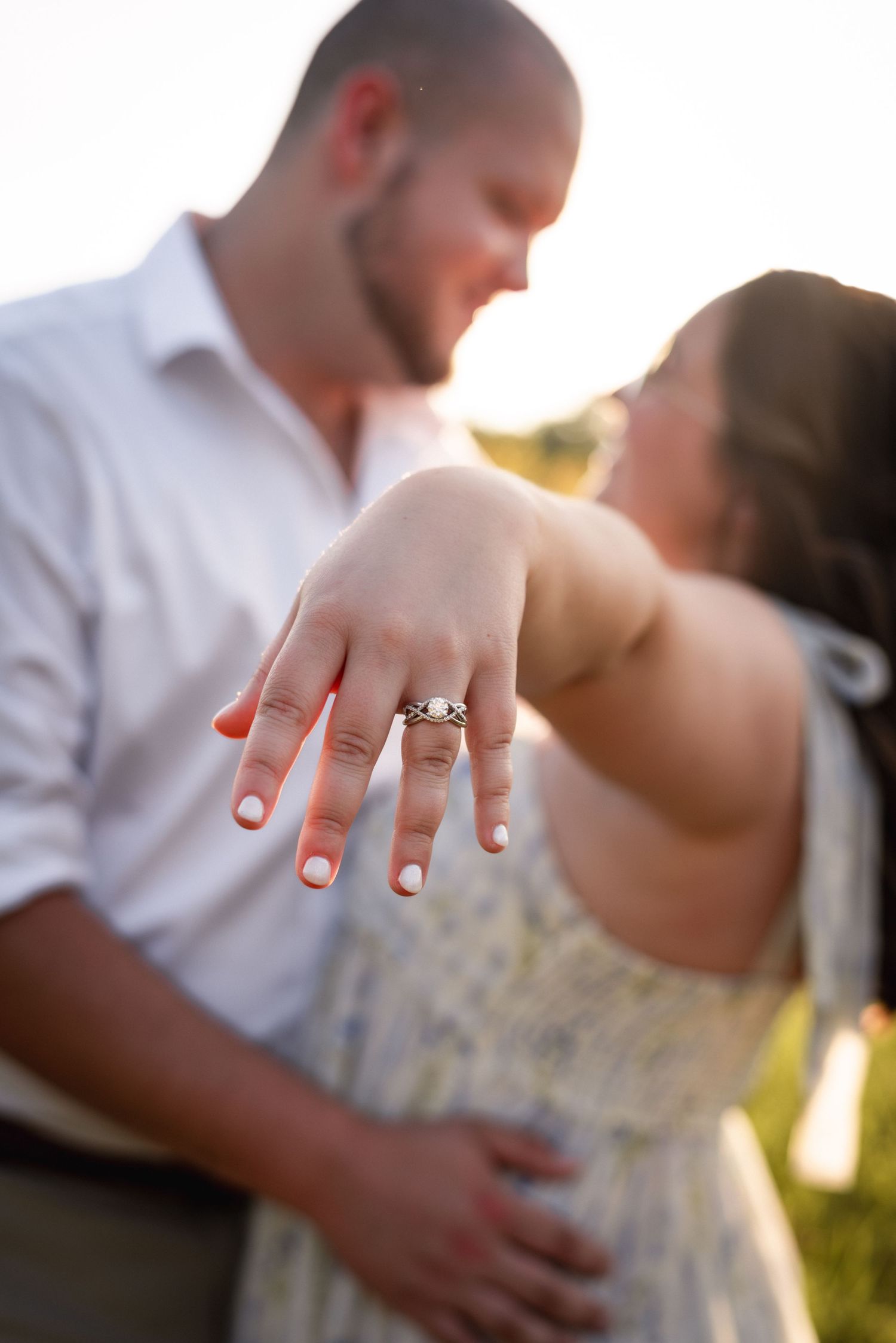 Romantic engagement photos showing hands with rings in golden sunlight.