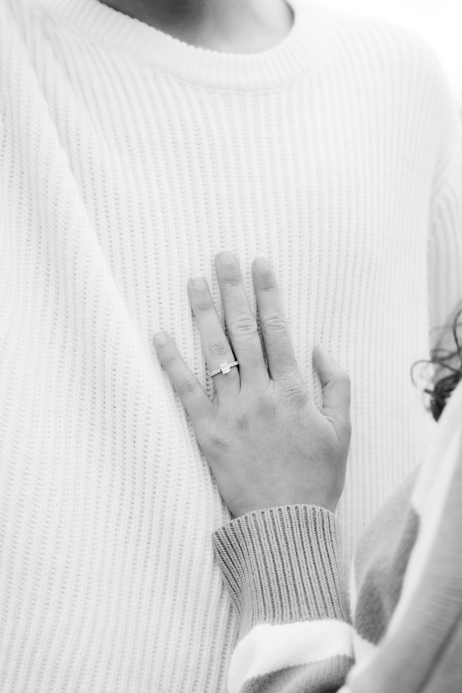 Close-up shots of hands showing off an engagement ring against white sweater.