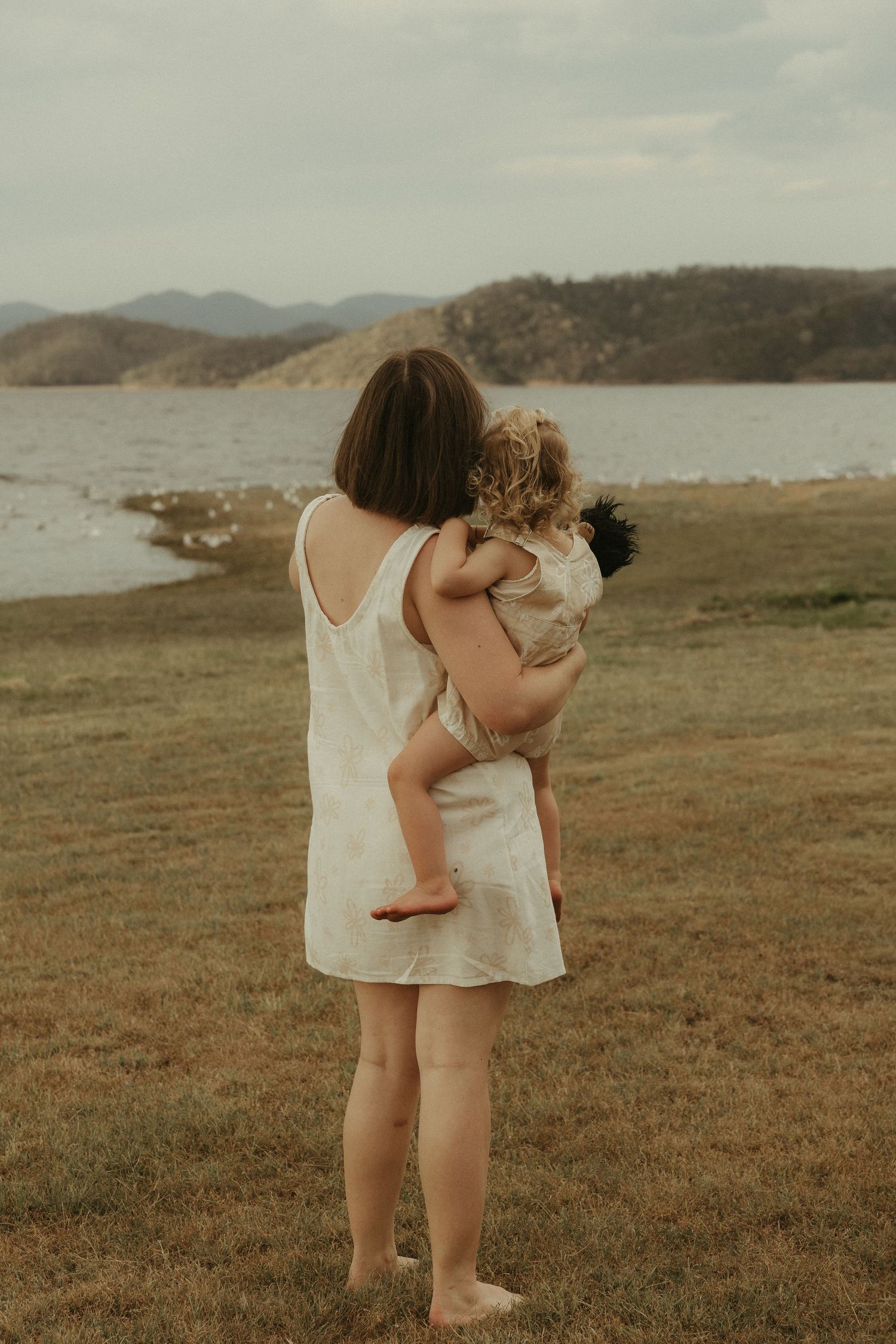 Mother holding toddler near water
Mother embracing toddler during a heartfelt family session by the lake in Ipswich.