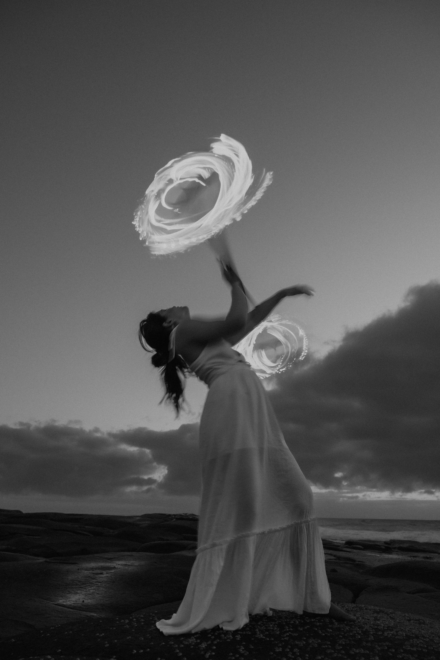 Woman dancing with fire stick
Woman dancing with fire stick in dramatic black-and-white portrait captured at sunrise on the Sunshine Coast