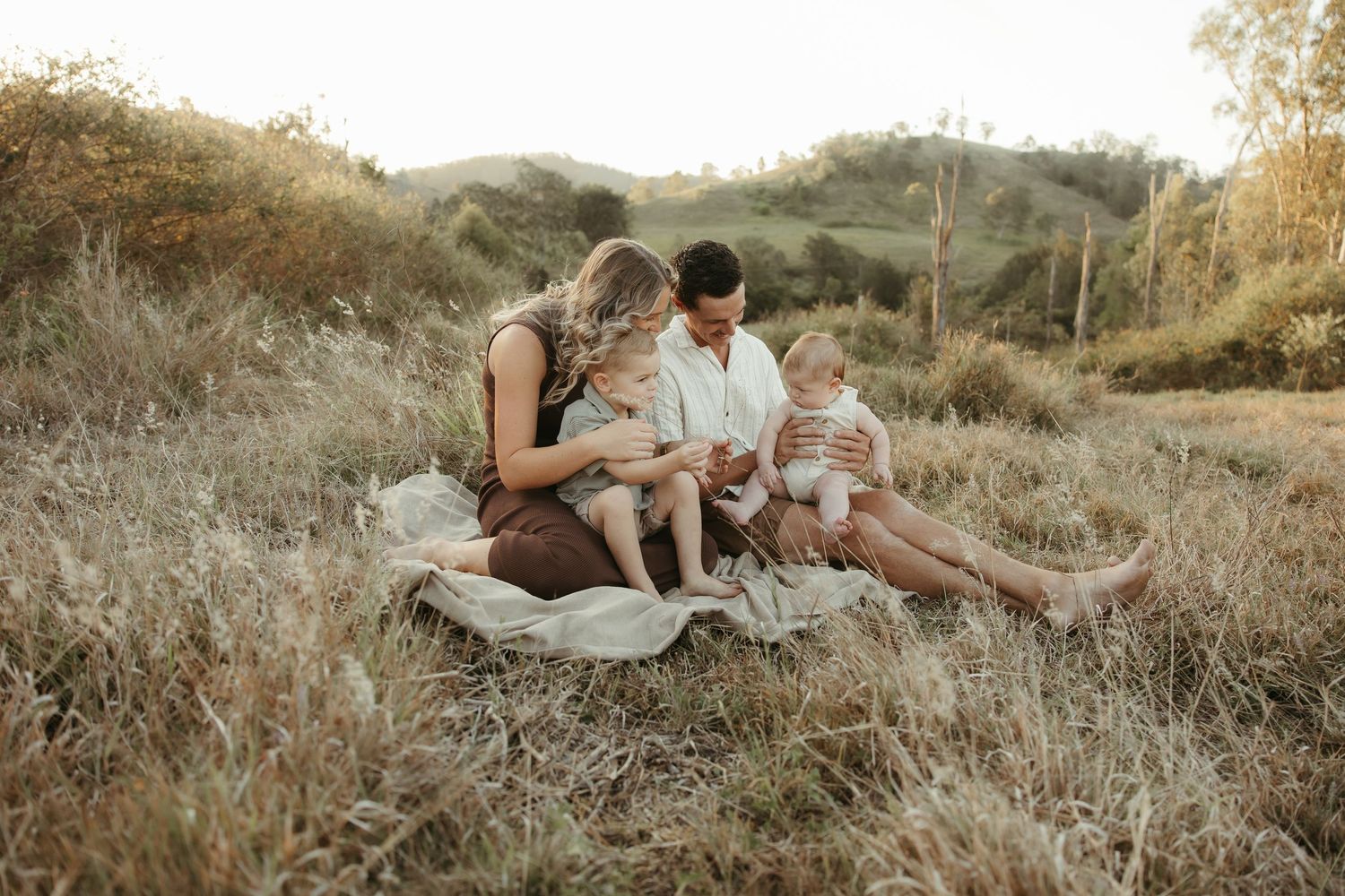 Family sitting on blanket outdoors
Family sitting together on a blanket during a relaxed outdoor family photography session.
