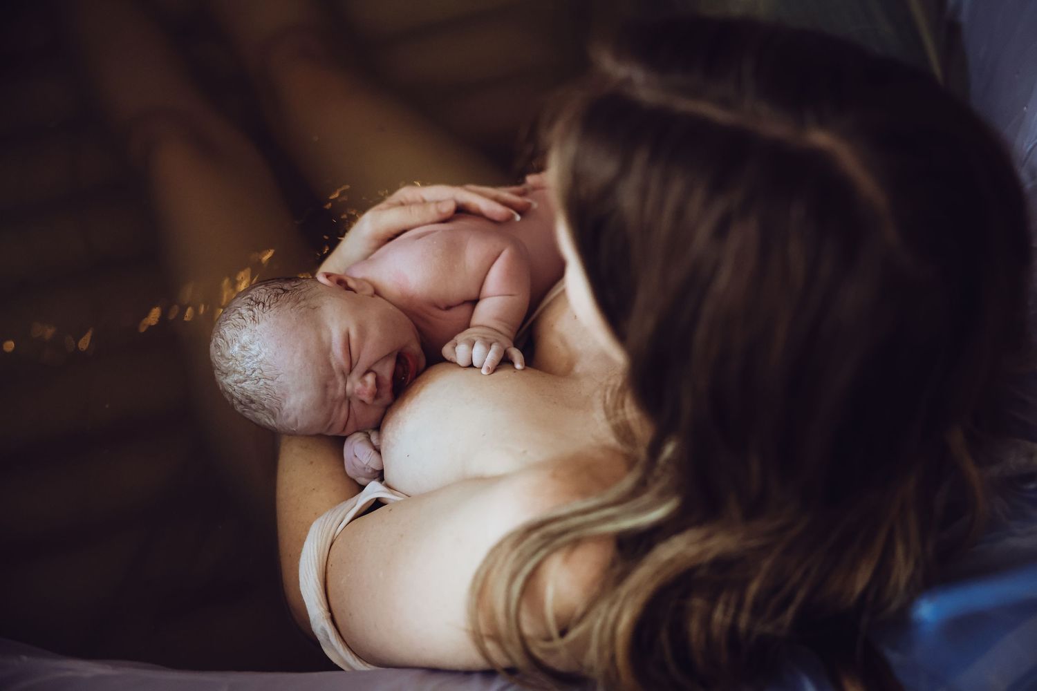 Mother holding newborn in water
Mother holding newborn in birth pool moments after delivery during a homebirth session. Waterbirth.Homebirth