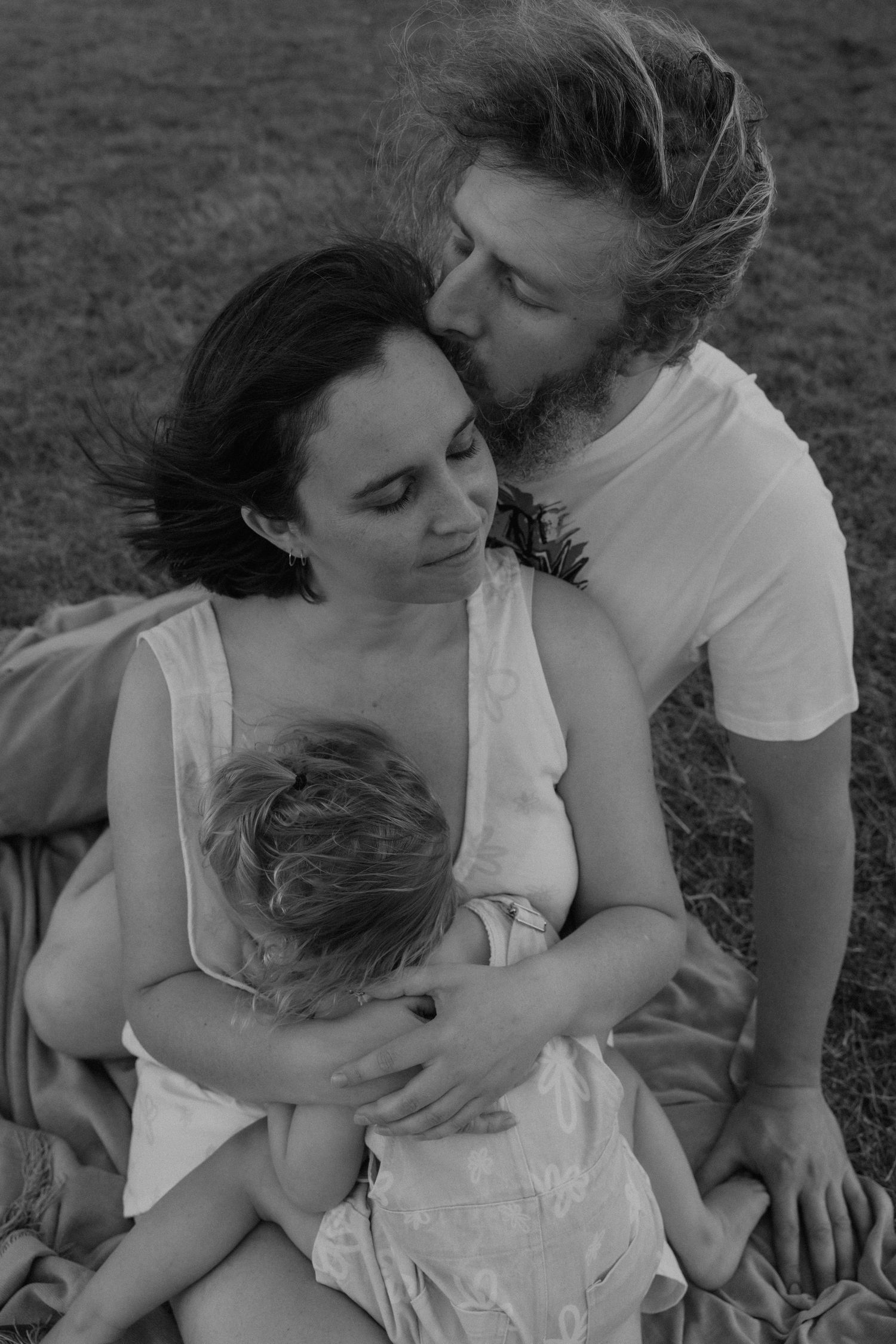 Parents cuddling toddler, black and white
Parents holding their toddler closely in a tender black-and-white family portrait.