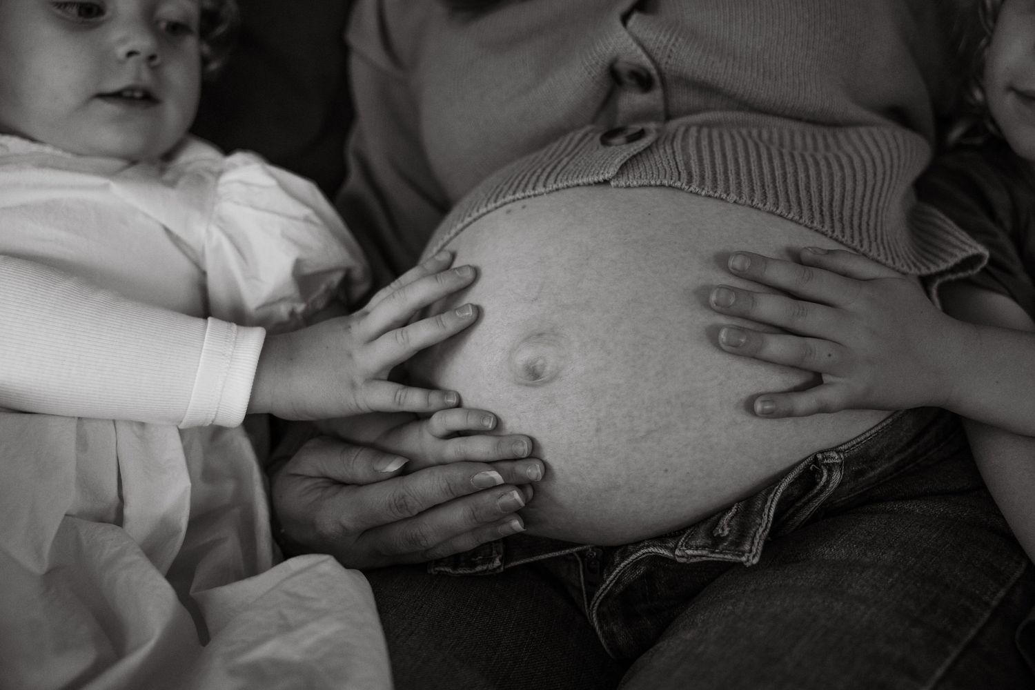 Hands on pregnant belly with toddler
Family hands resting on pregnant belly during a maternity session featuring siblings in Ipswich.